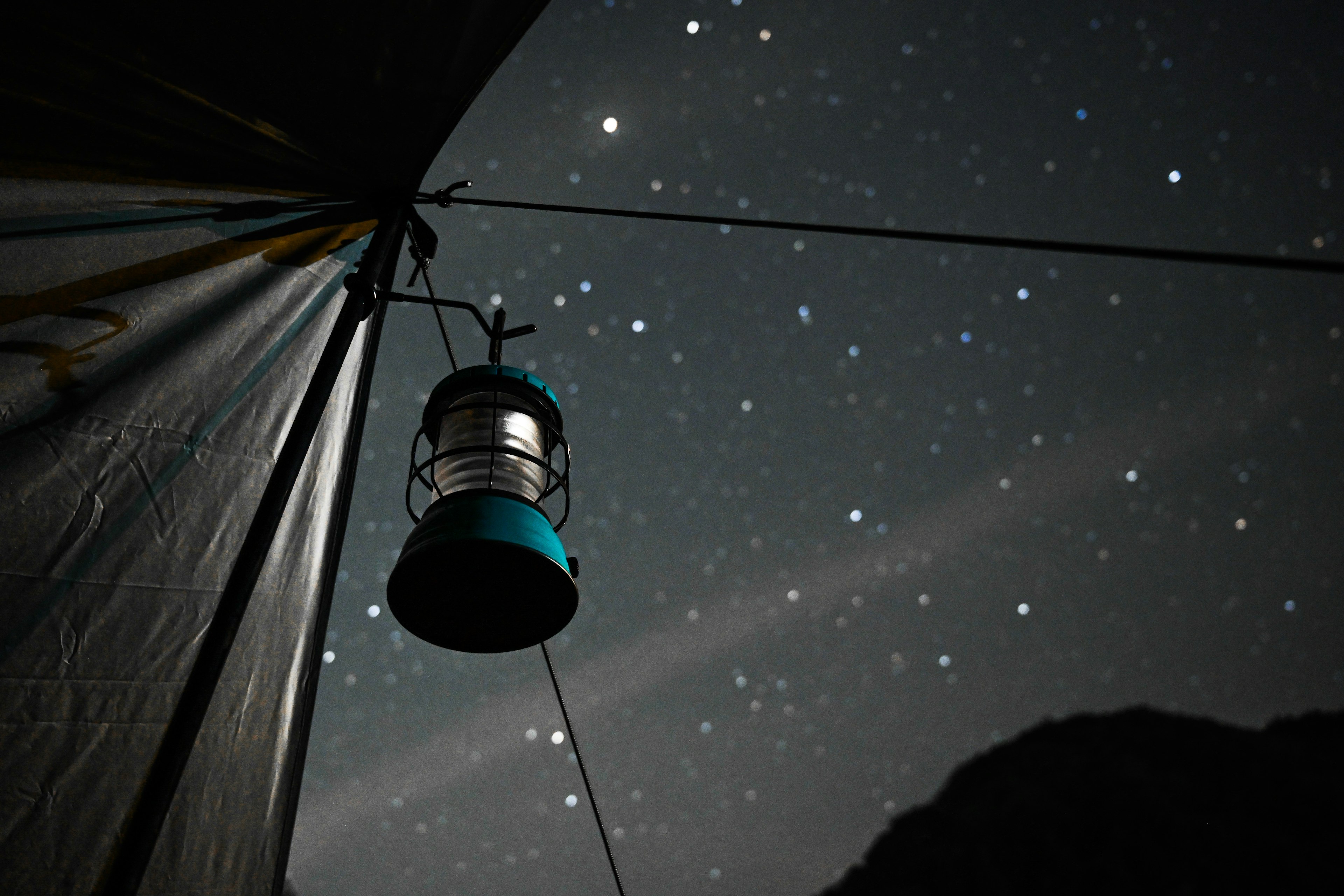 A blue lantern hanging outside a tent under a beautiful starry night sky