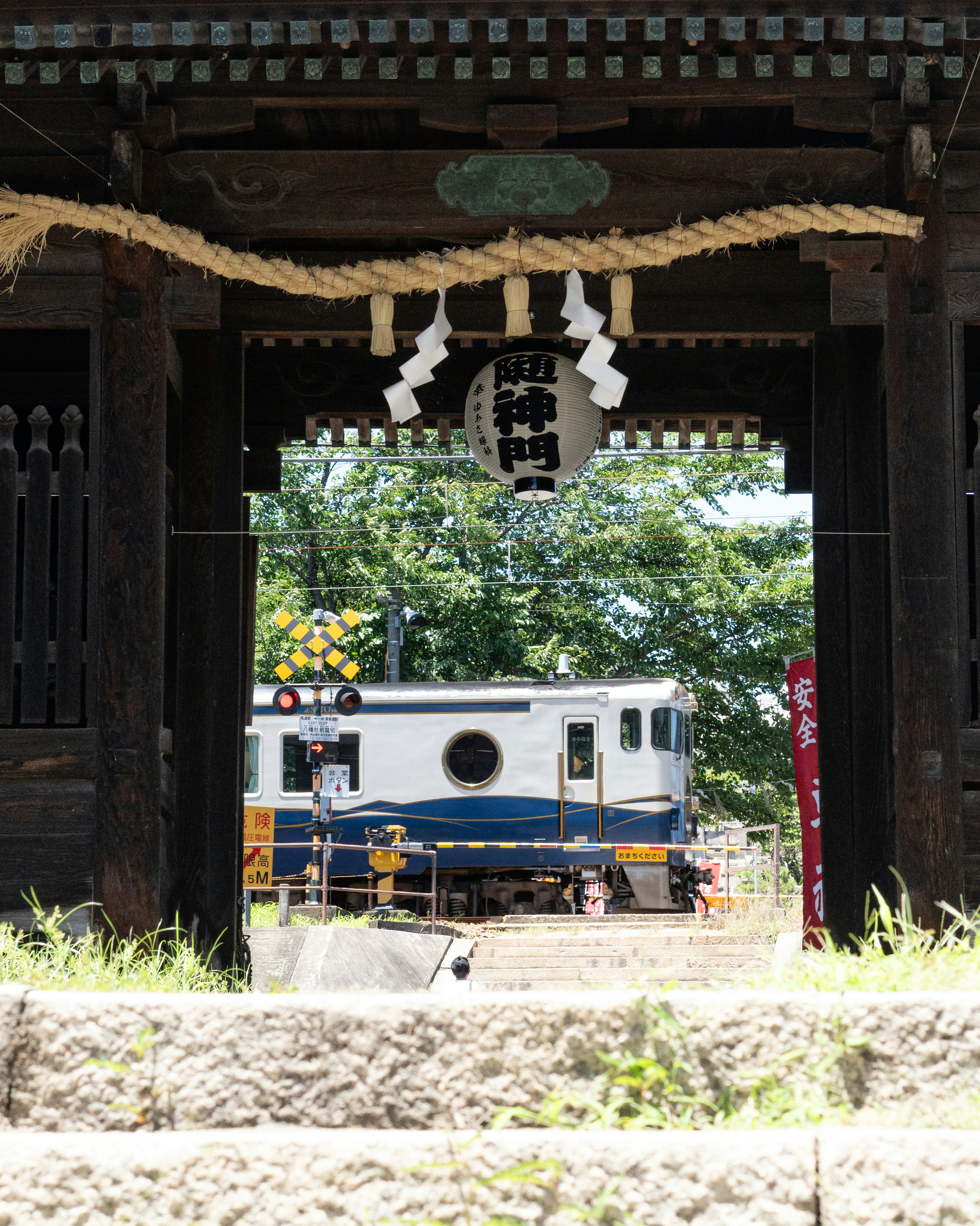 透过古老神社门看到的火车和绿色景观