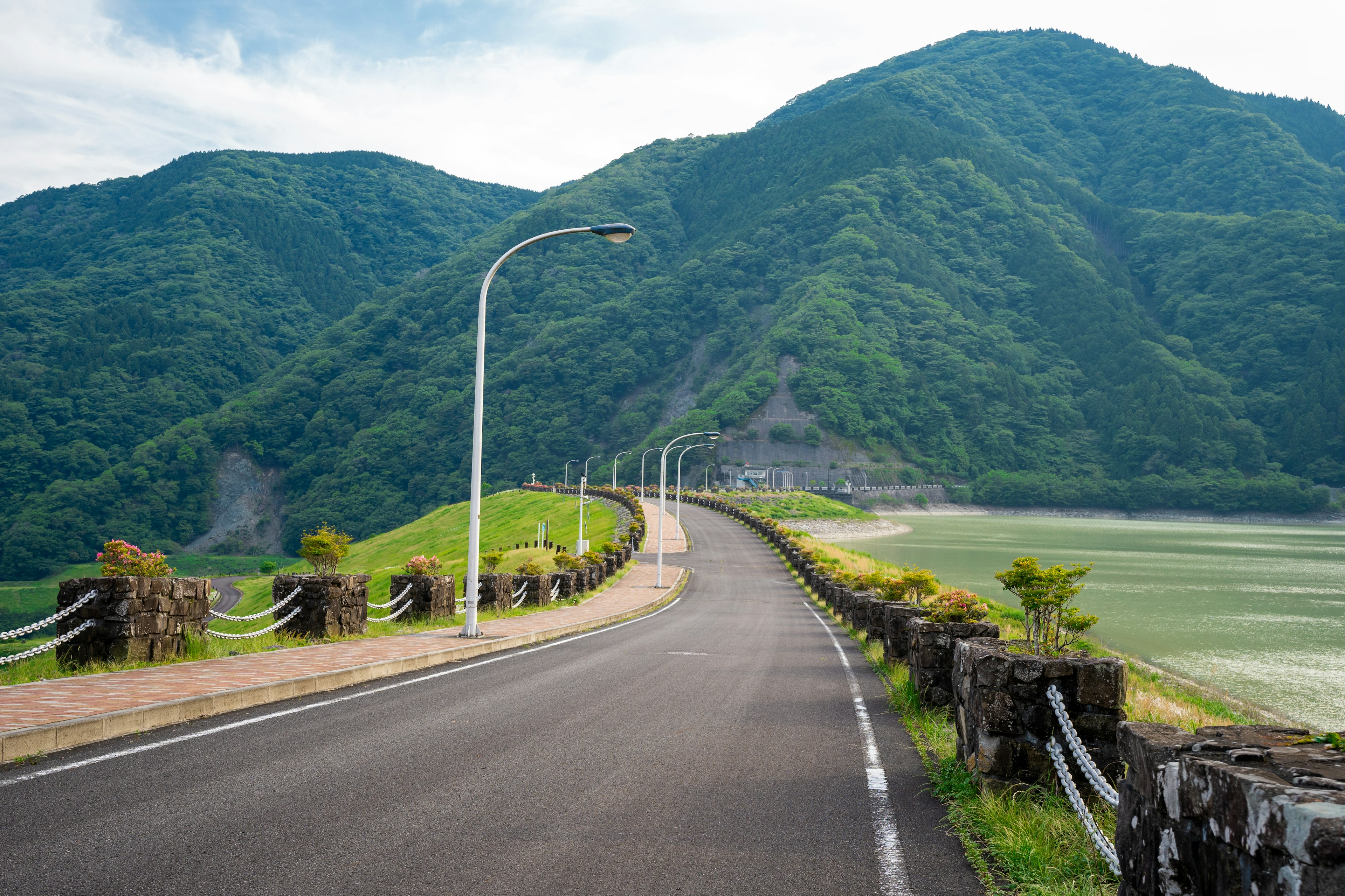 緑豊かな山々に囲まれたカーブした道路の風景