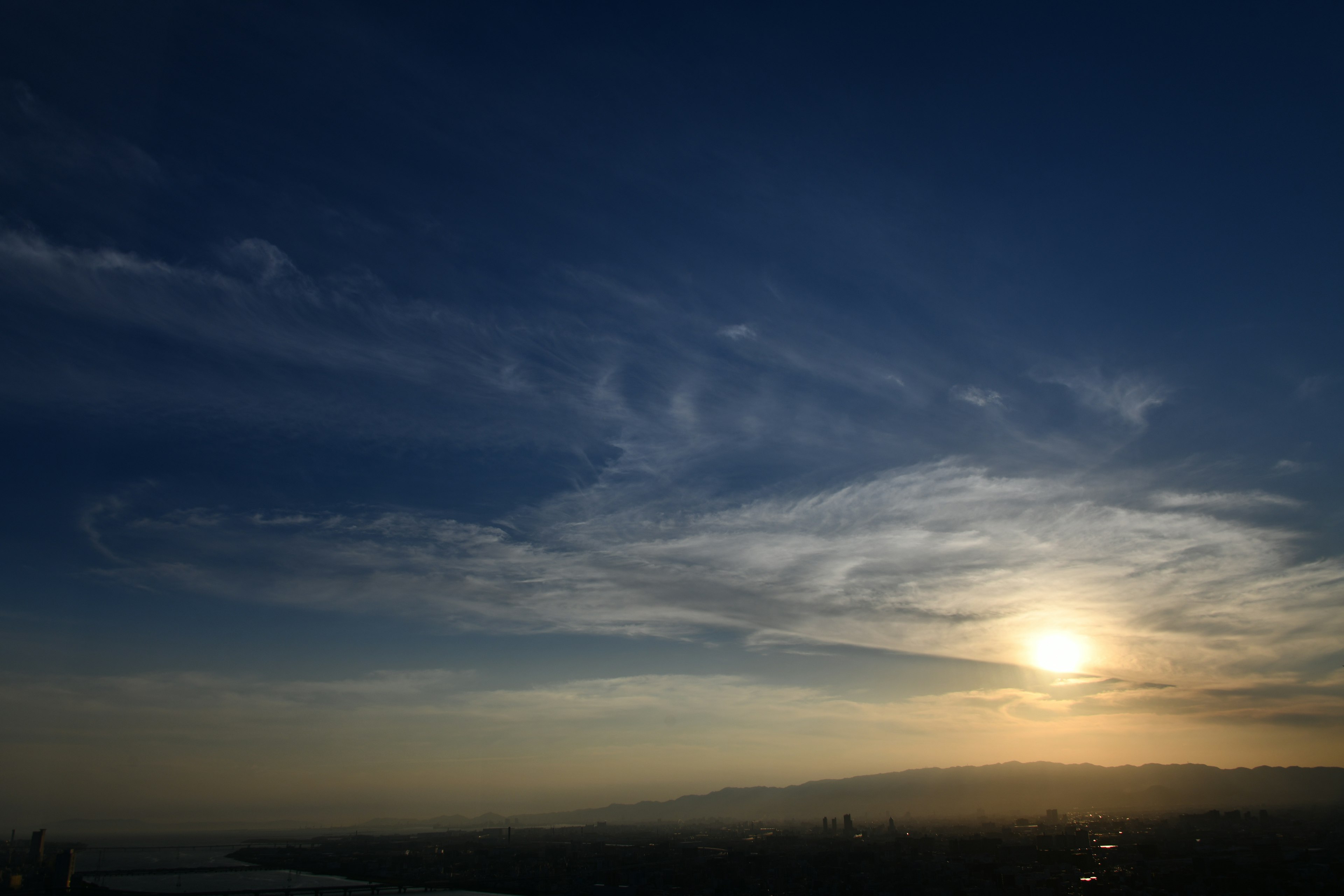 Blauer Himmel mit Wolken und untergehender Sonne