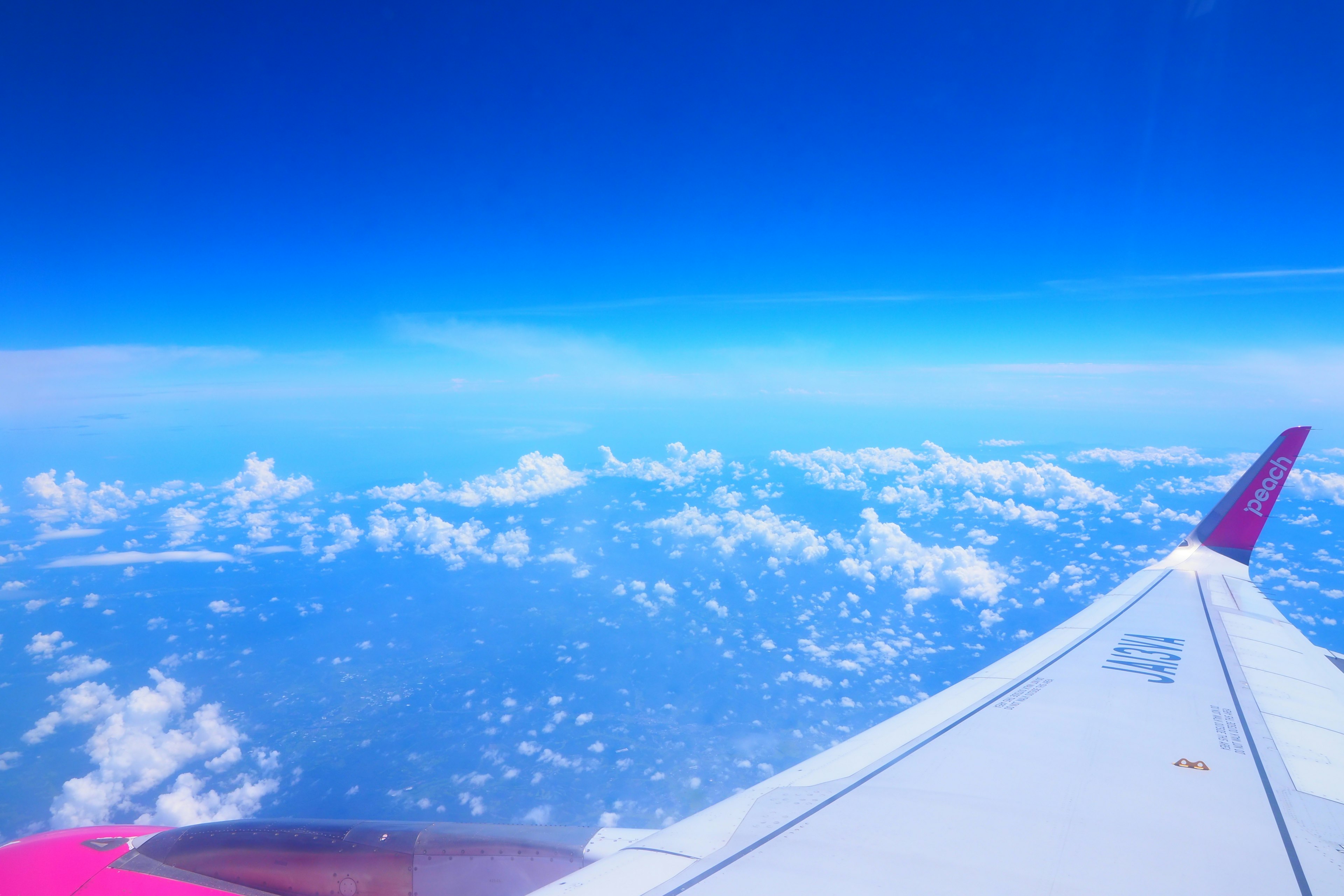 View from an airplane wing showcasing a bright blue sky and fluffy clouds