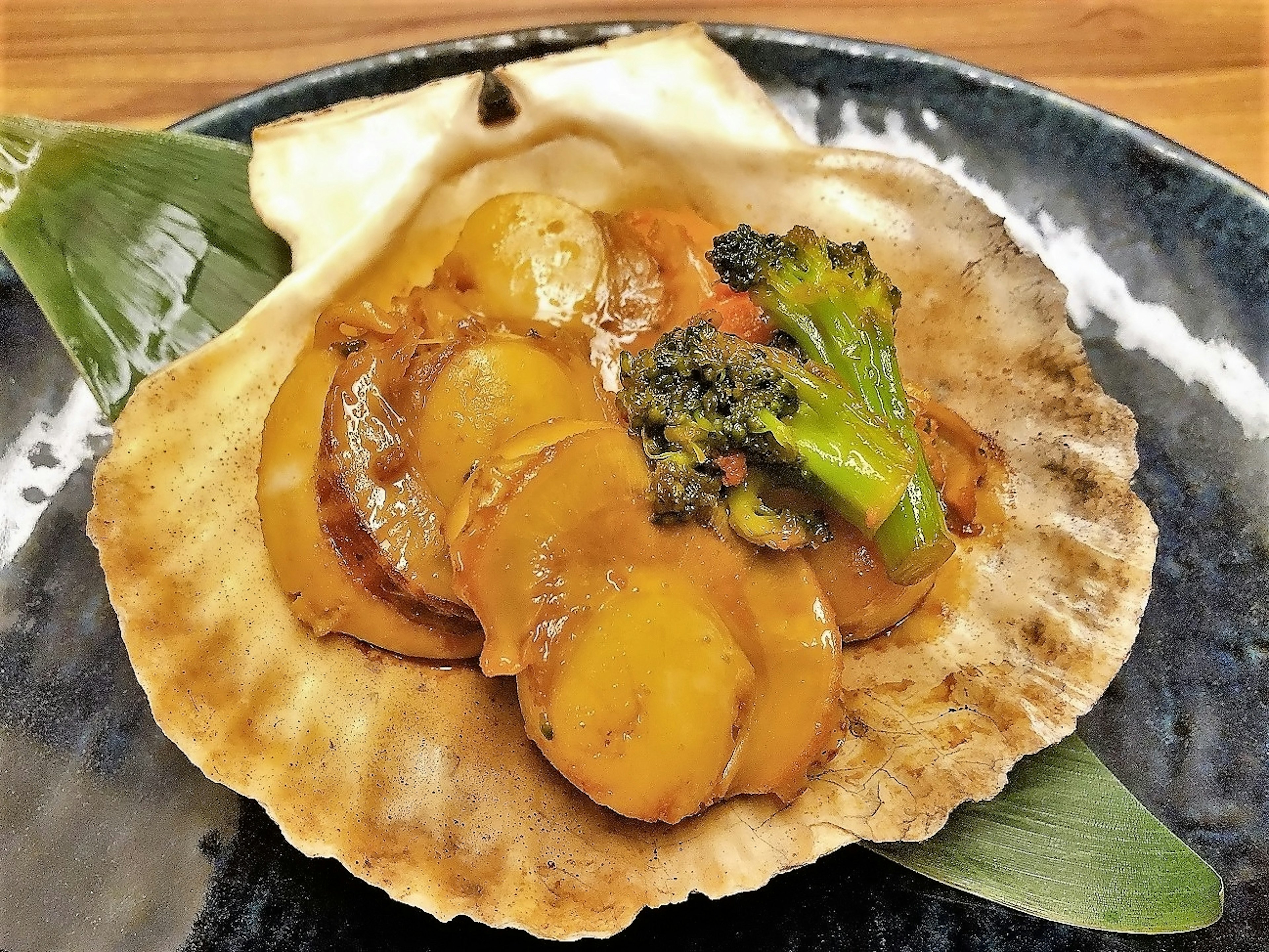 Plat servi dans une coquille avec des fruits de mer, du brocoli et de la sauce