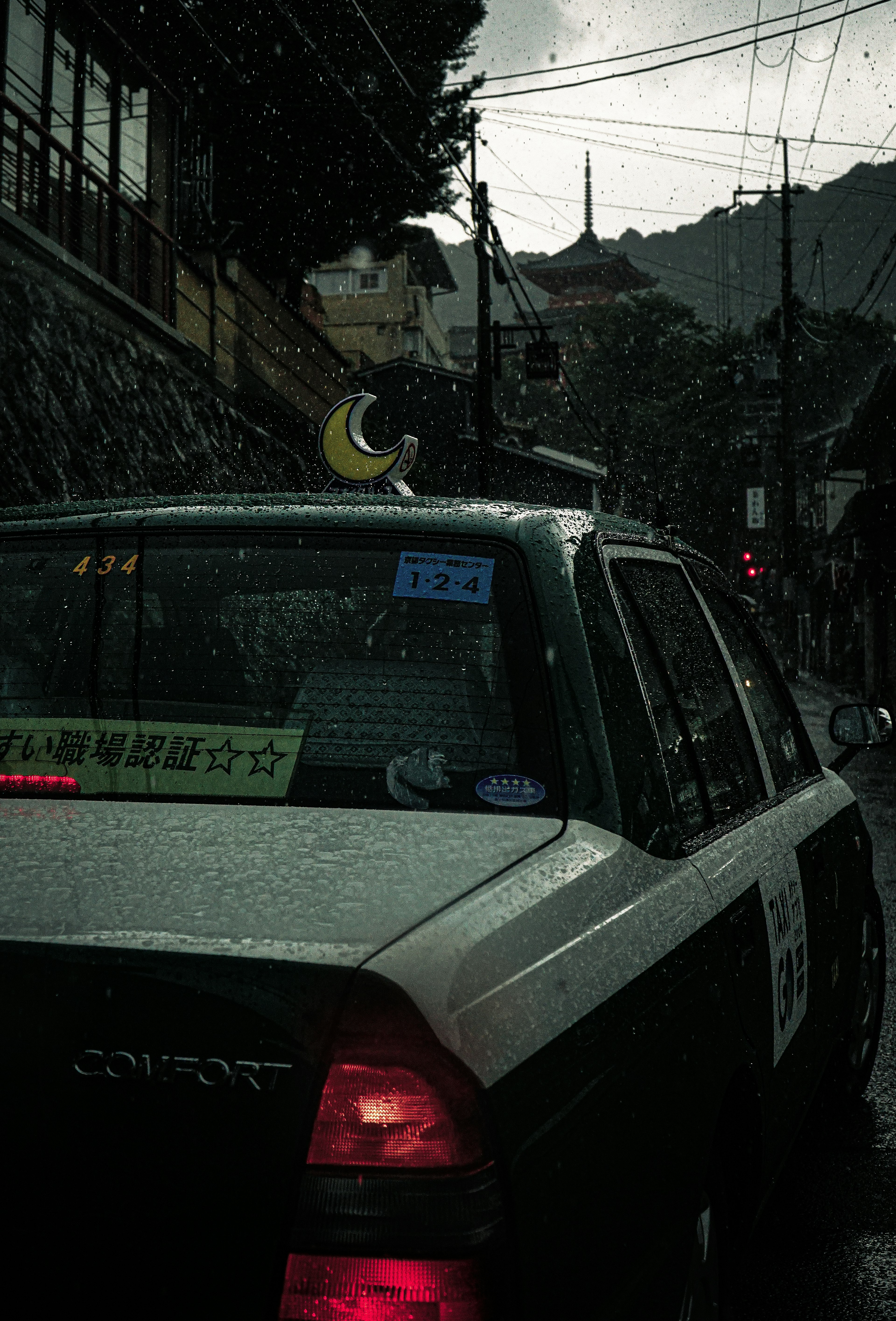 雨の中で走るタクシーの後ろ姿と周囲の風景