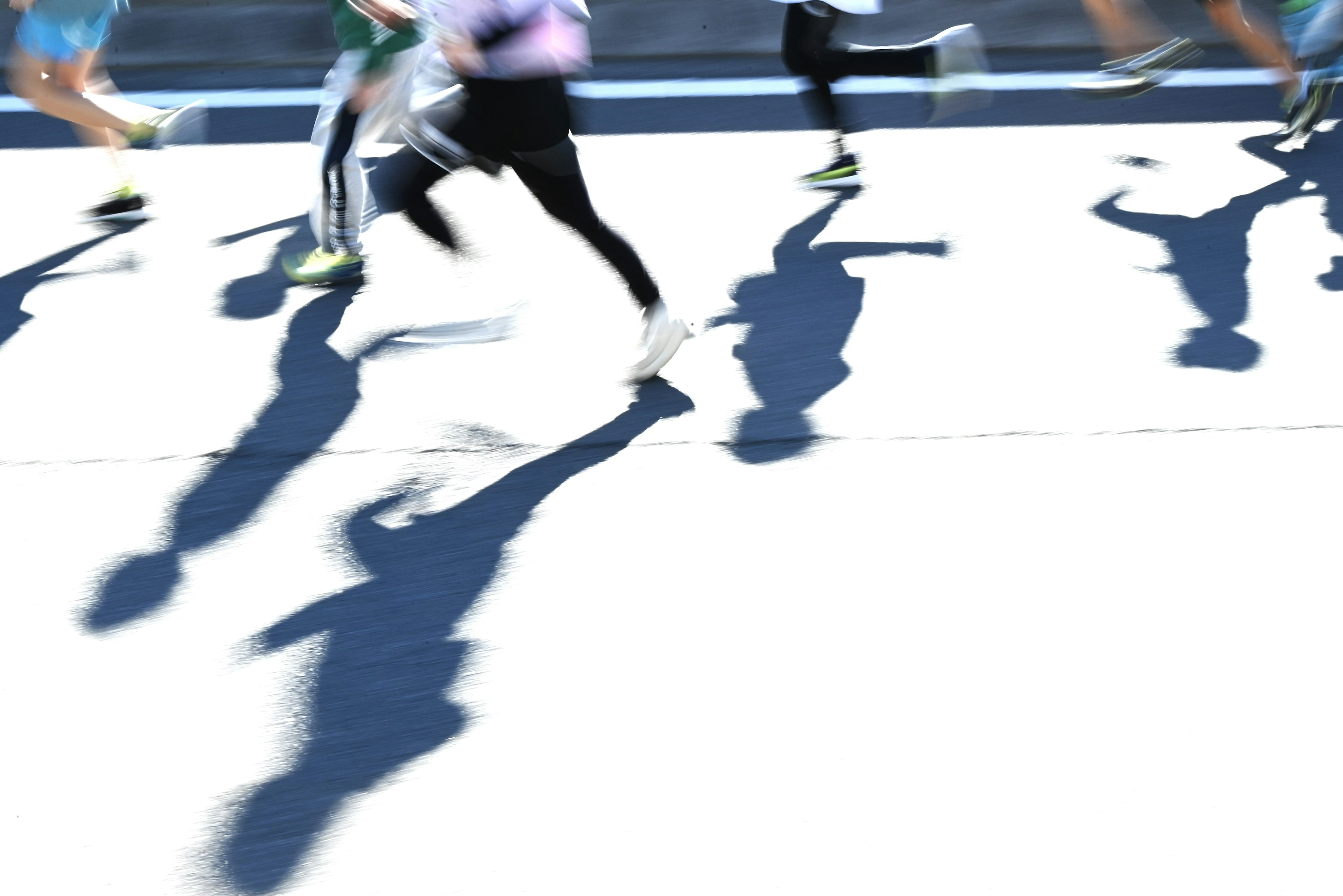 Shadows of running people on a bright pavement