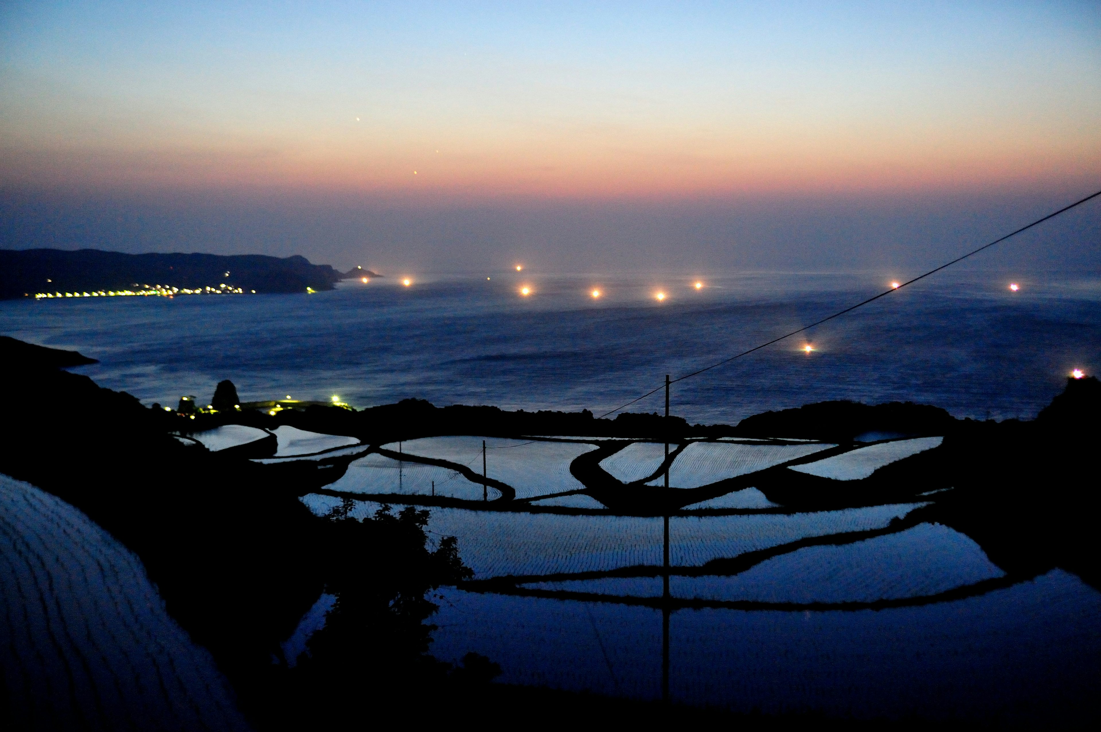 Scenic view of terraced rice fields and ocean at sunset