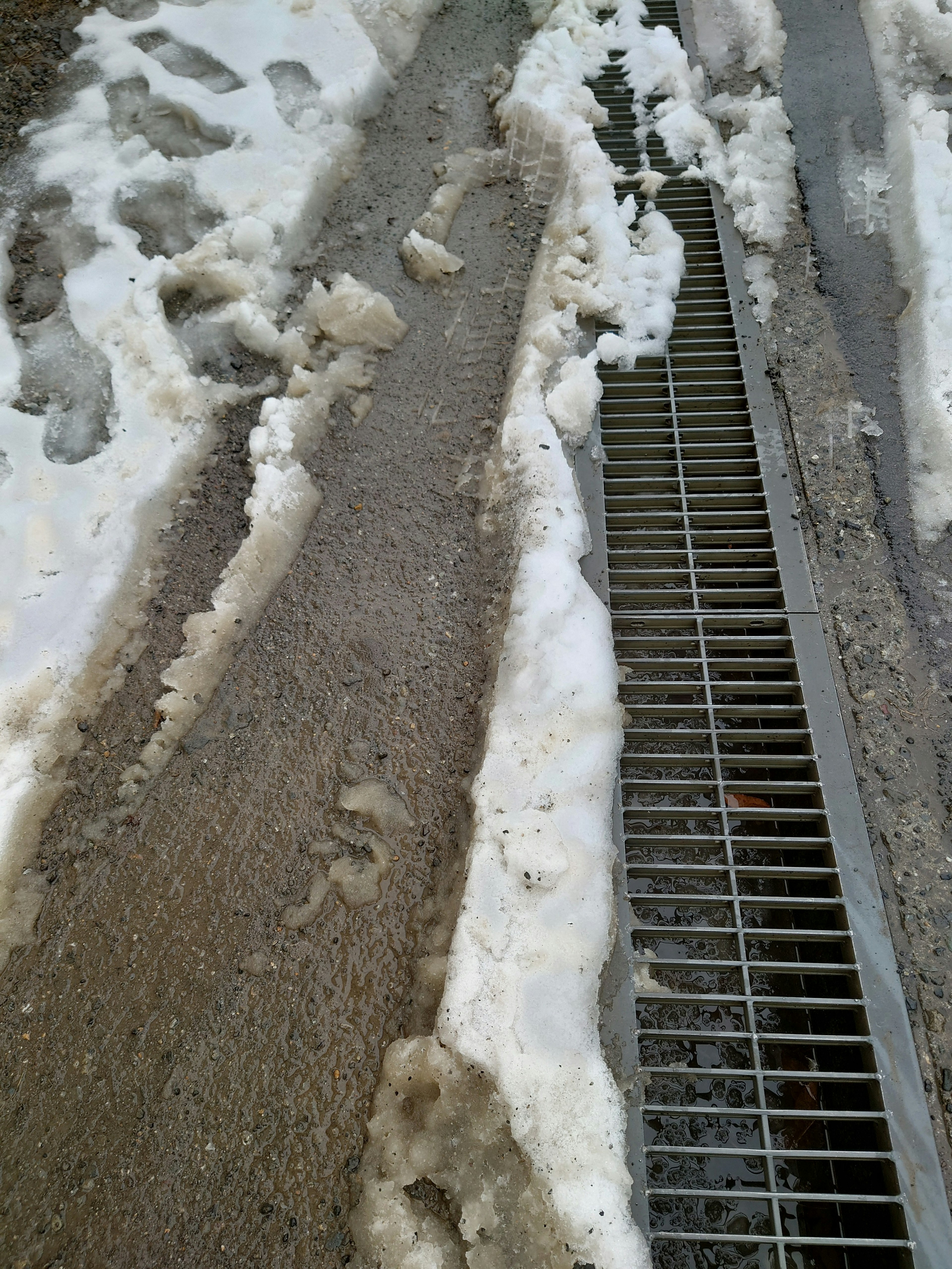 Immagine di un pavimento misto di neve e ghiaccio con una griglia di drenaggio