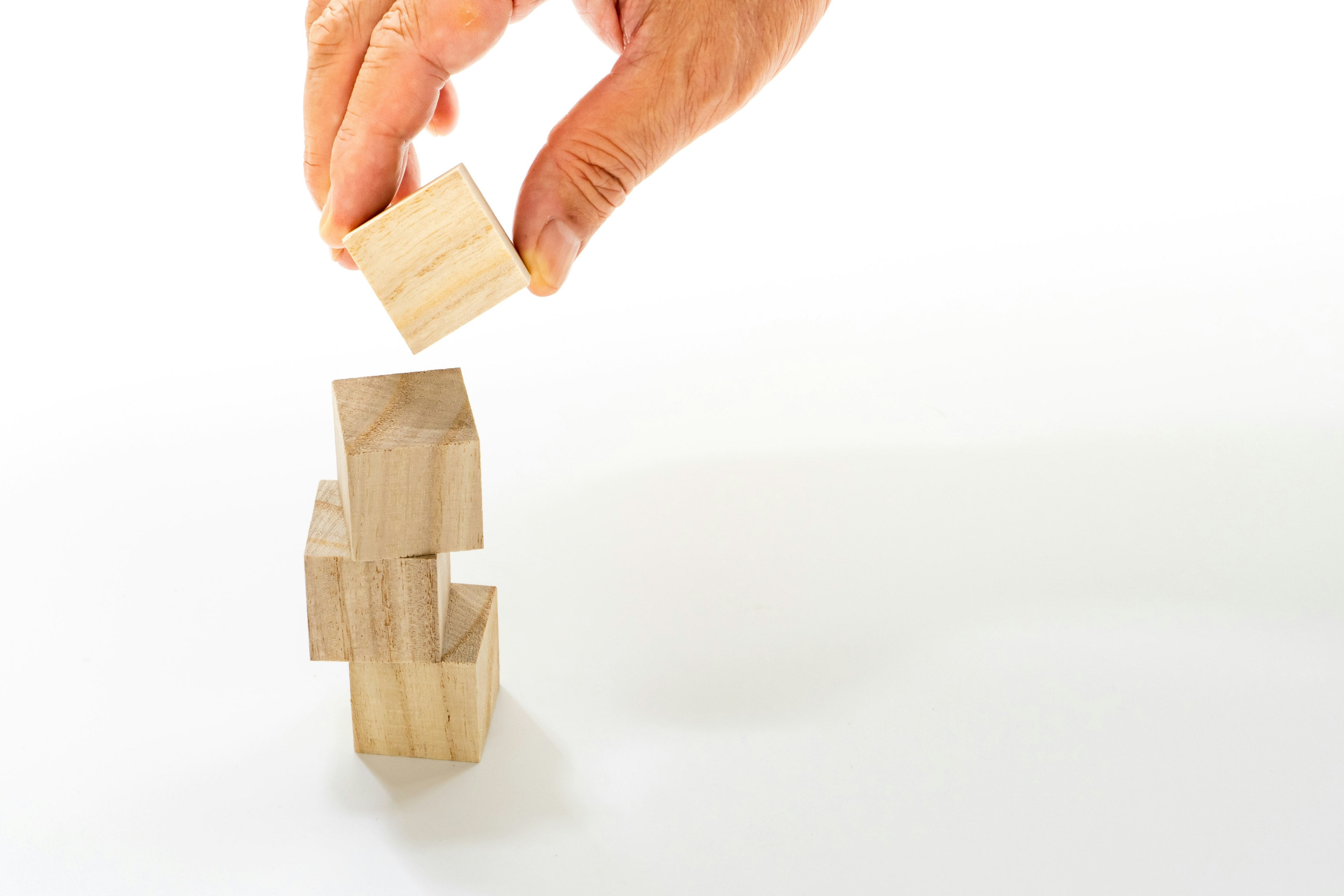 Main empilant des blocs en bois sur un fond blanc