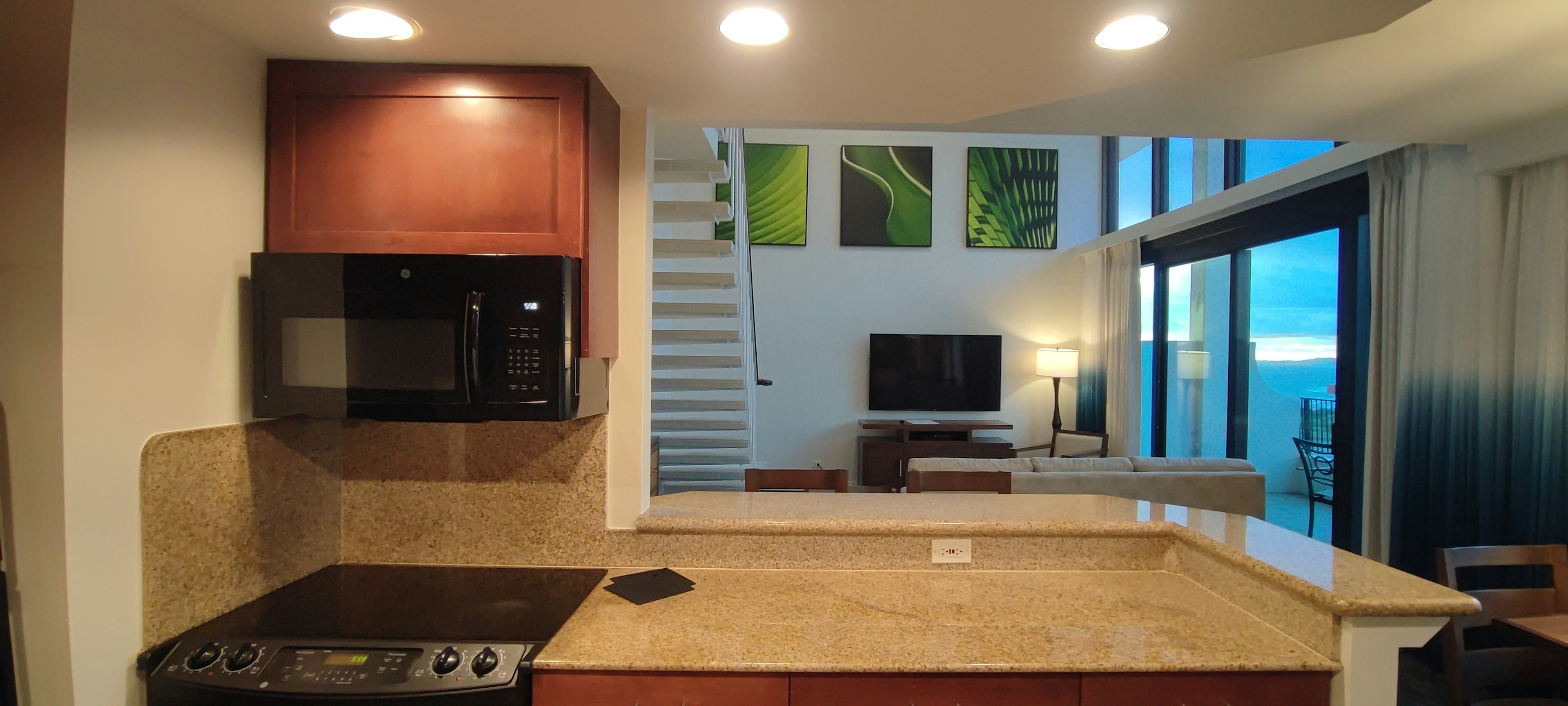 Interior de cocina moderna y sala de estar con iluminación nocturna y grandes ventanas