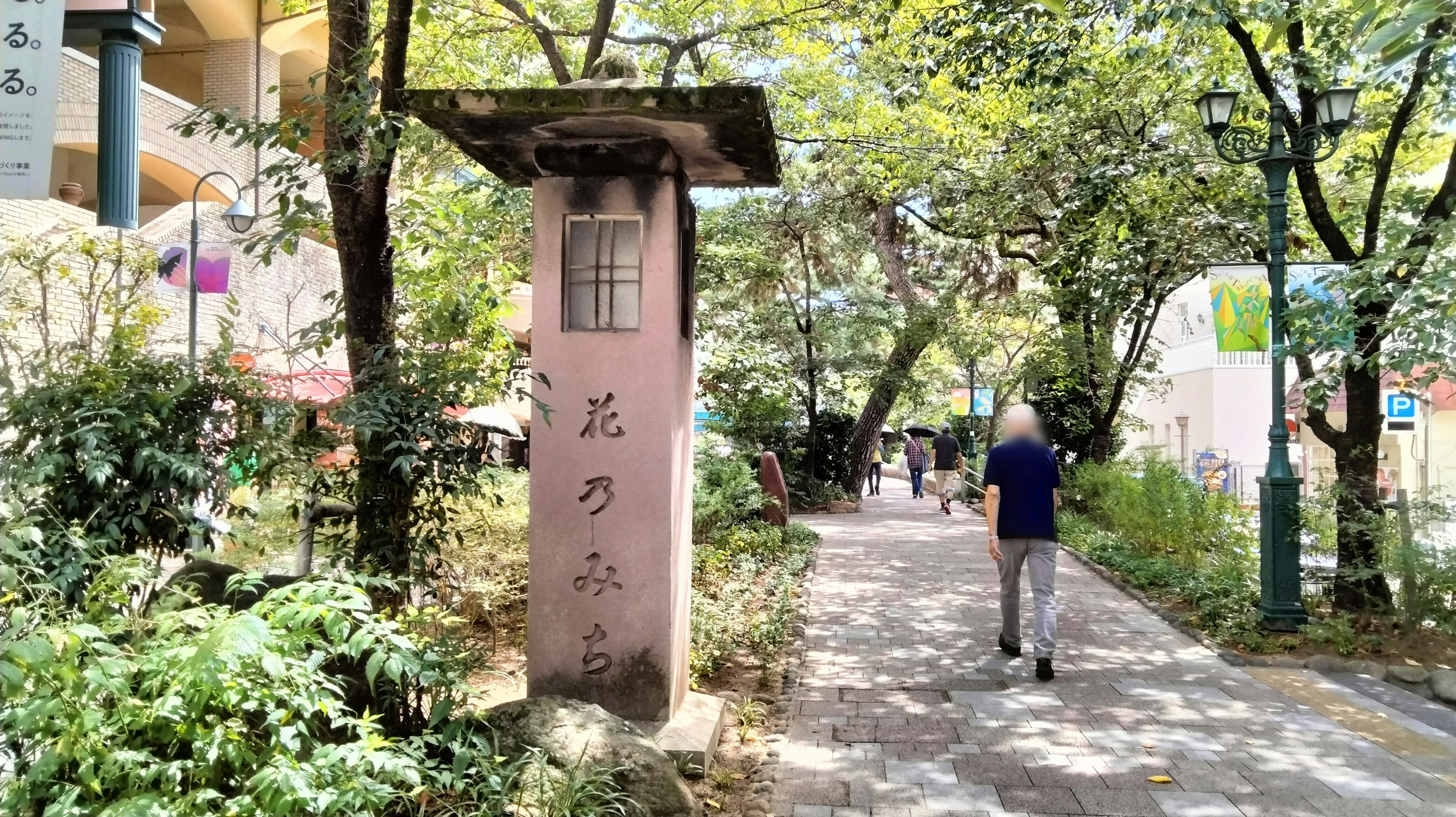 Monumento de piedra en un sendero de parque frondoso con una persona caminando