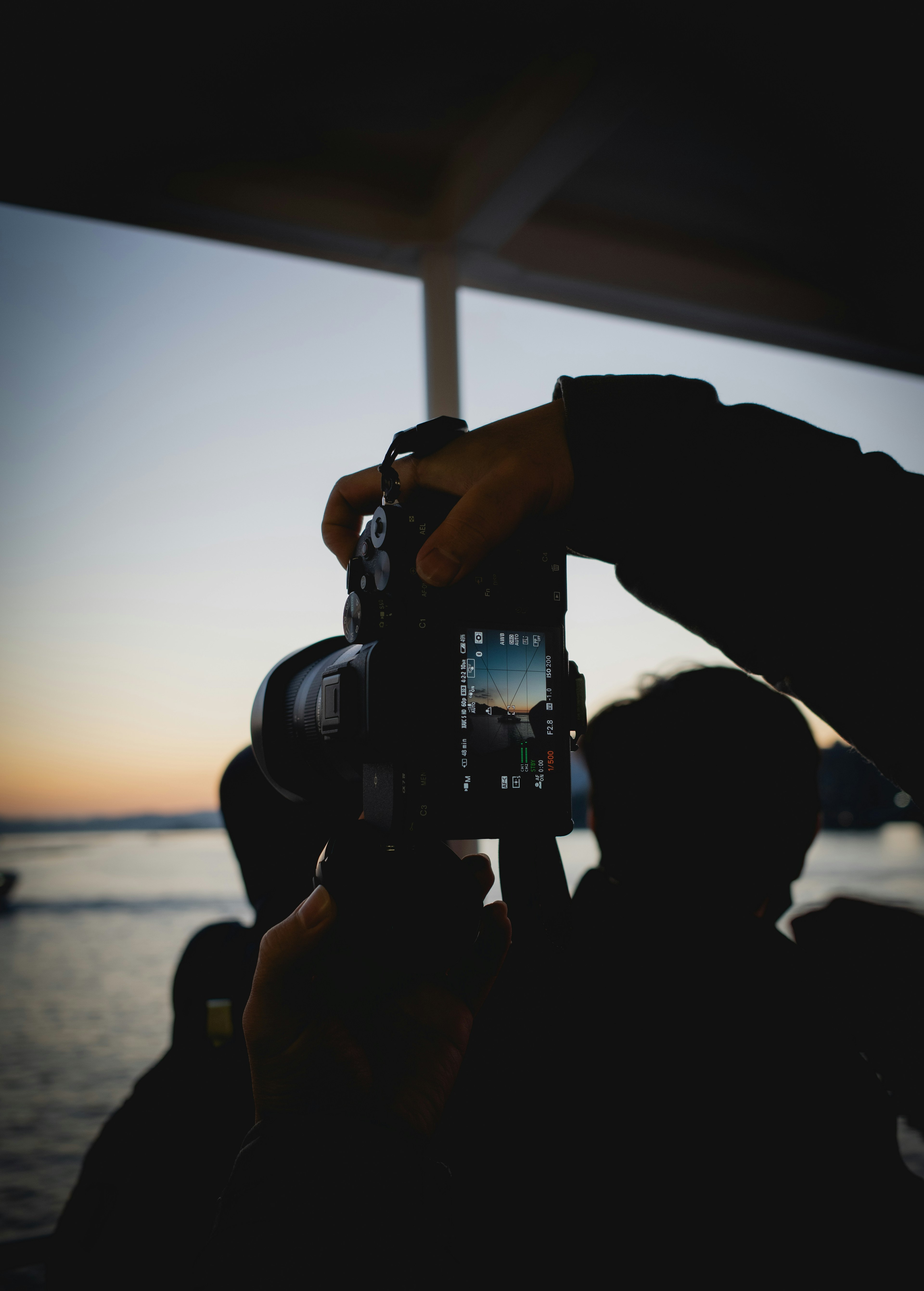 Silhouette of a person holding a camera against a sunset backdrop