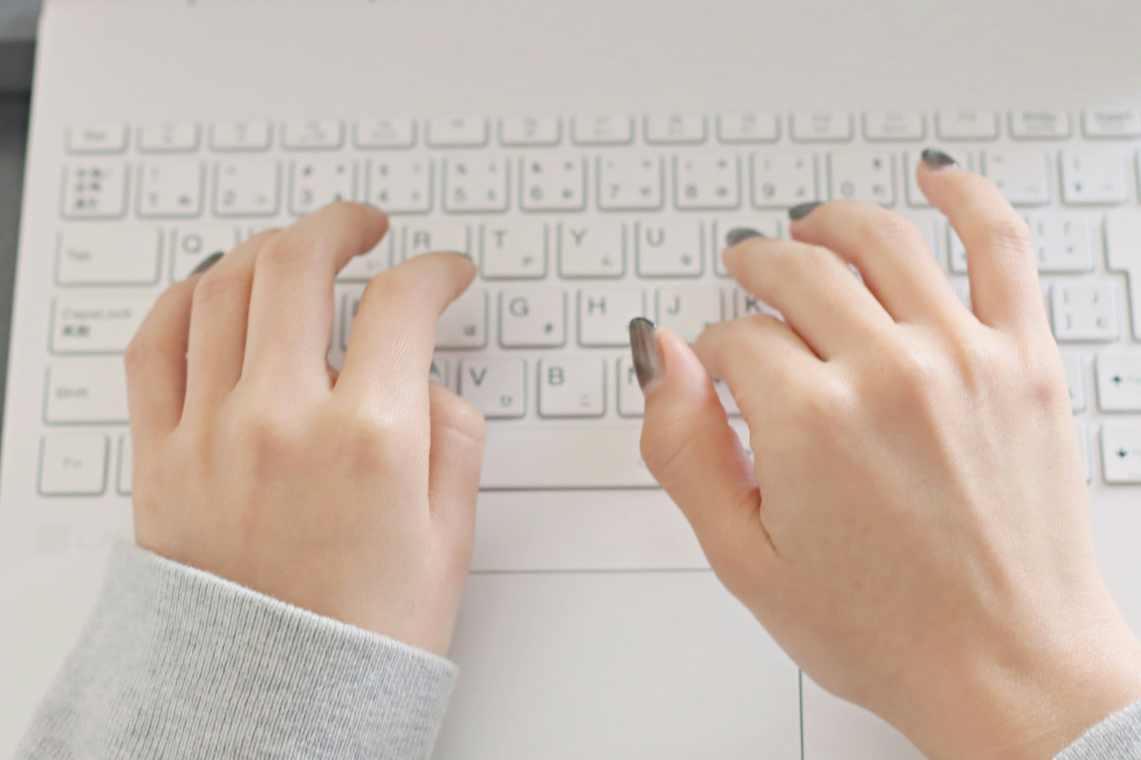 Close-up of hands typing on a laptop keyboard