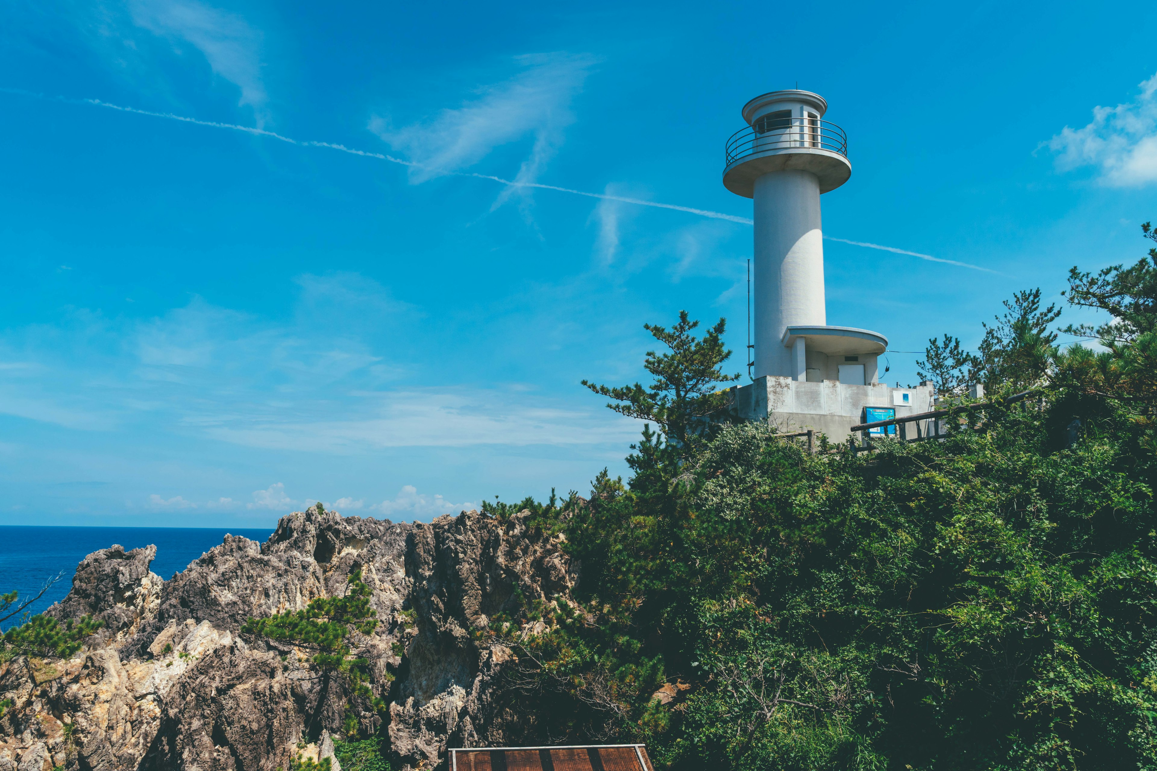 Phare se tenant sur une côte rocheuse sous un ciel bleu