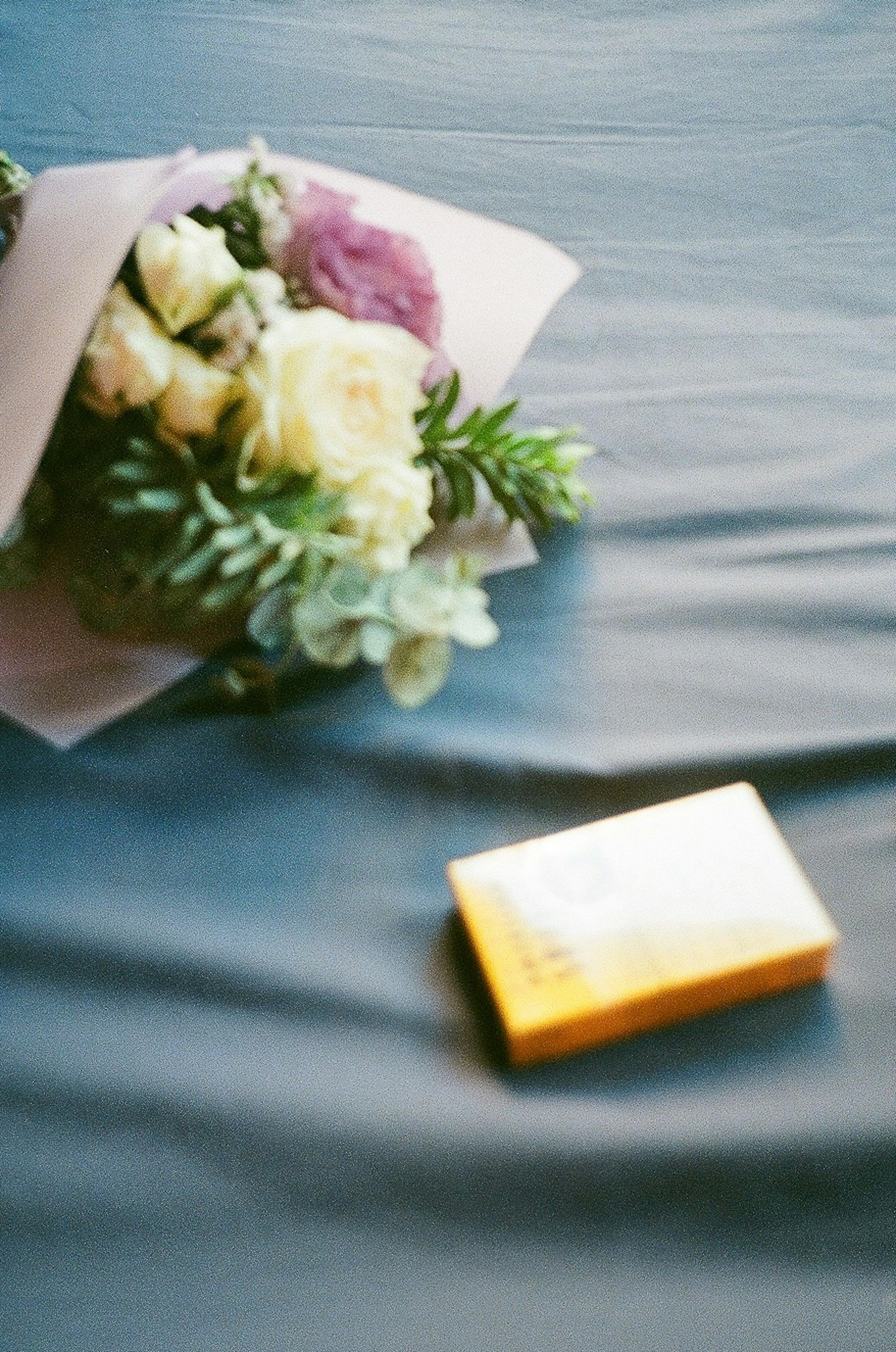 Un ramo de flores y una caja amarilla sobre una tela azul