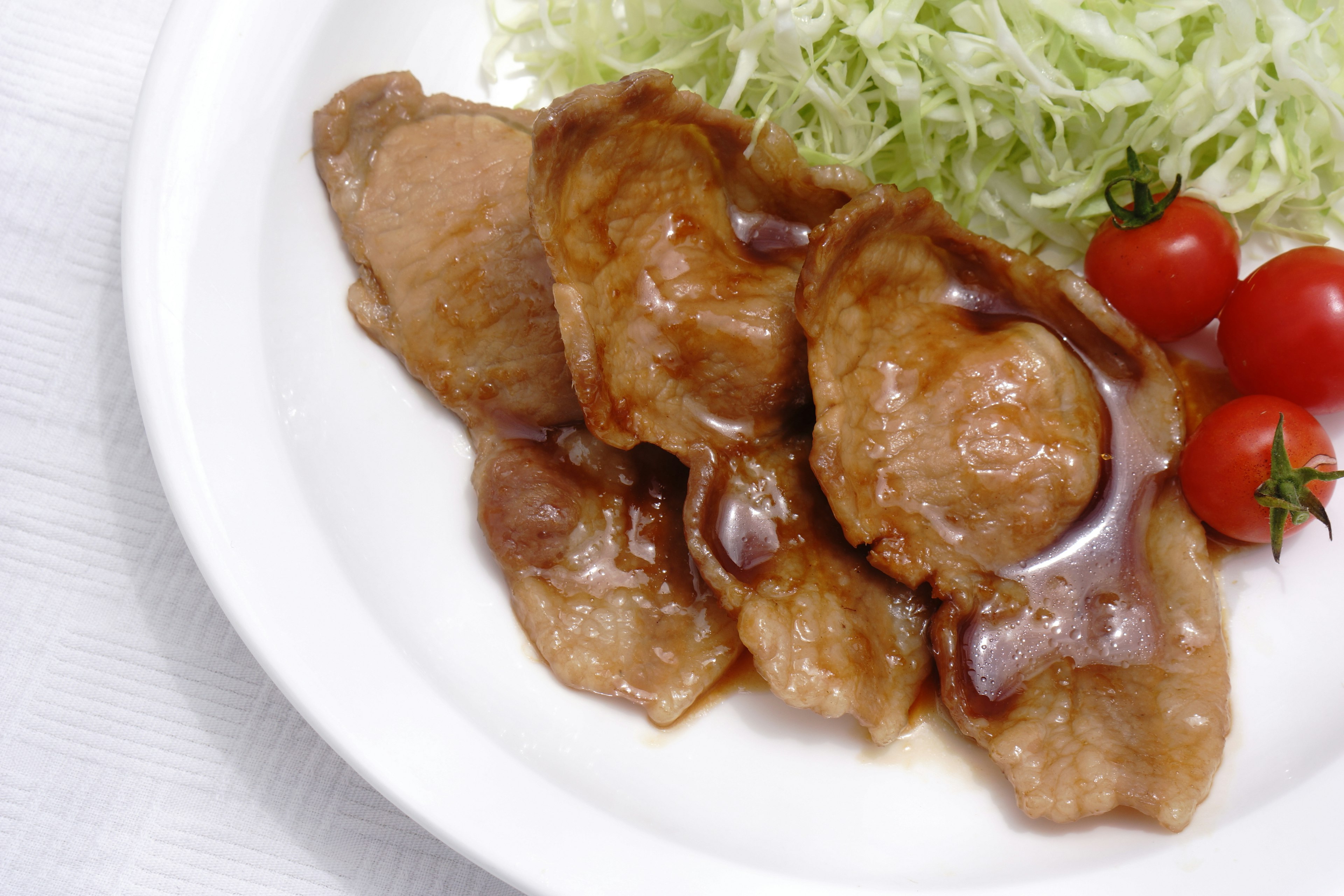 Rodajas de cerdo con repollo y tomates cherry en un plato