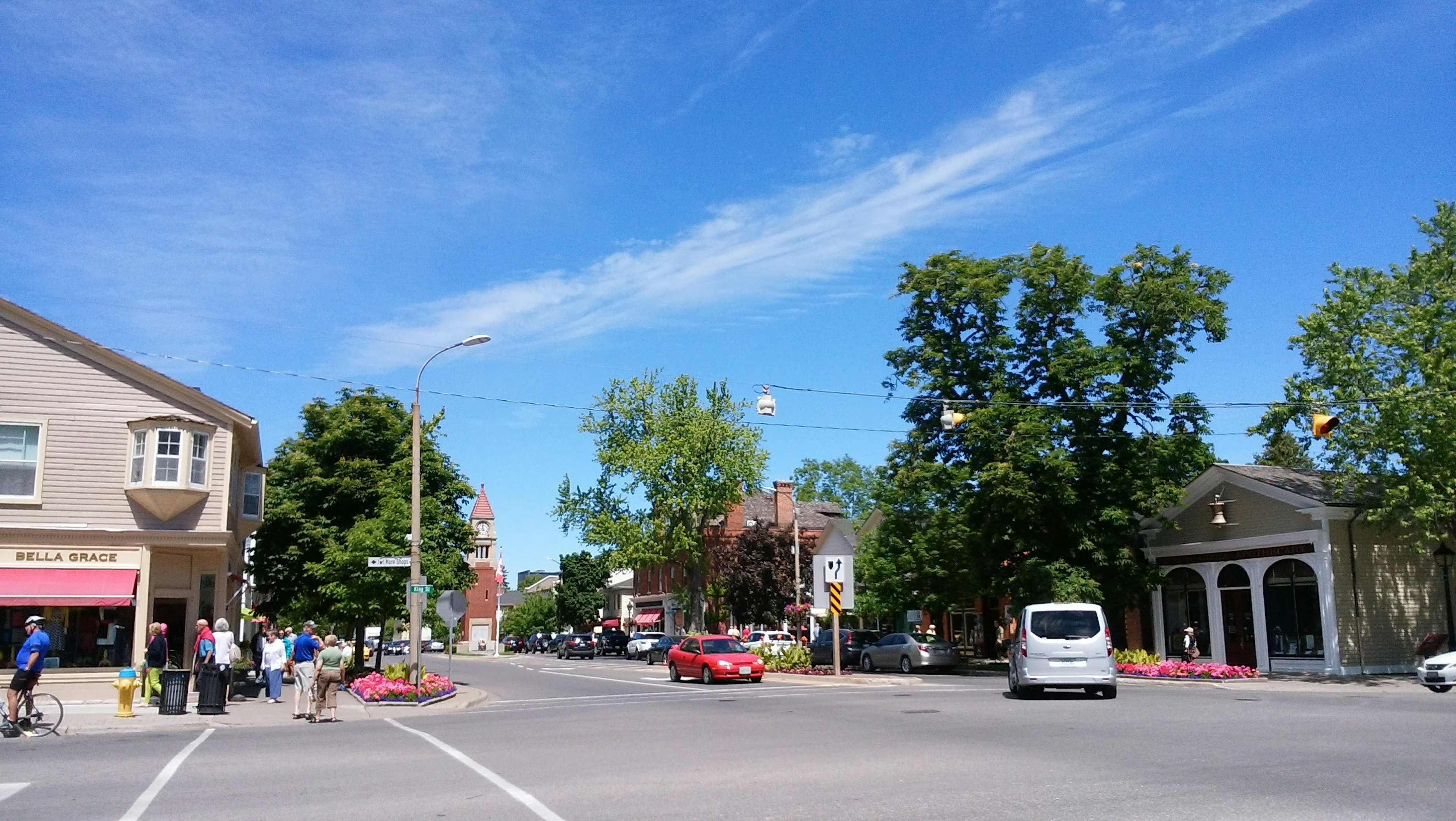 A busy street intersection with people and vehicles under a blue sky