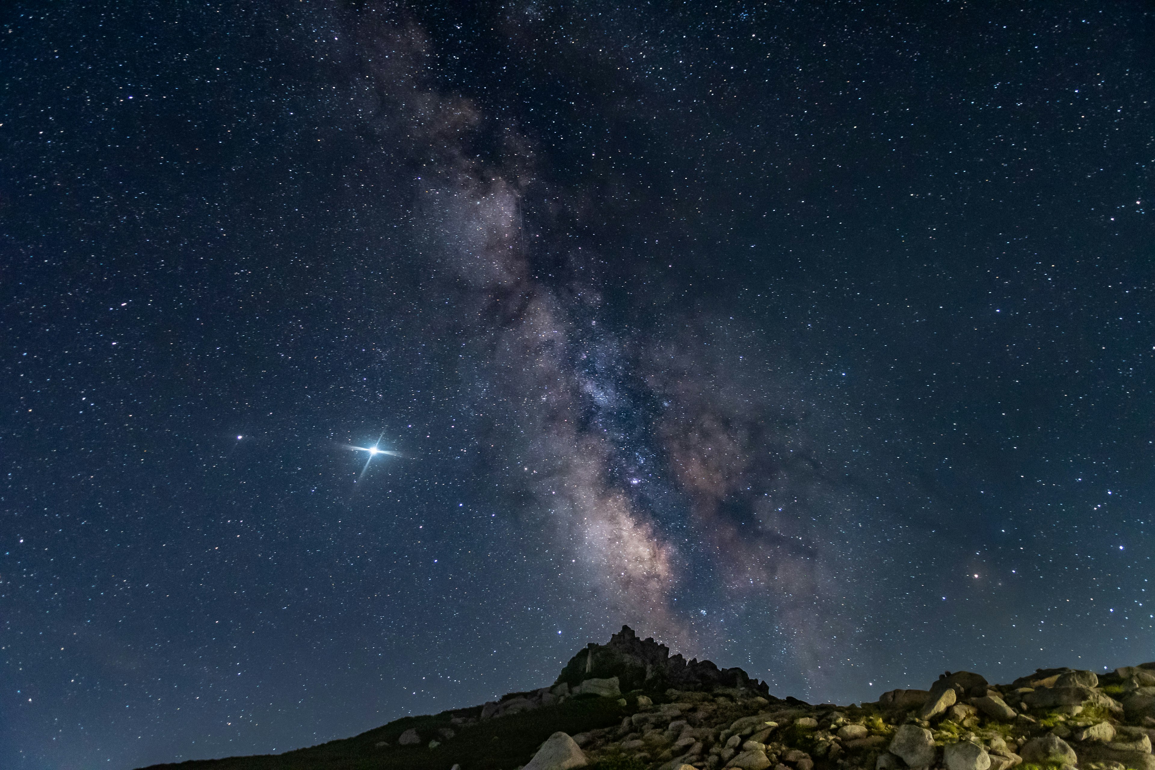 夜空中延伸的銀河與岩石前景