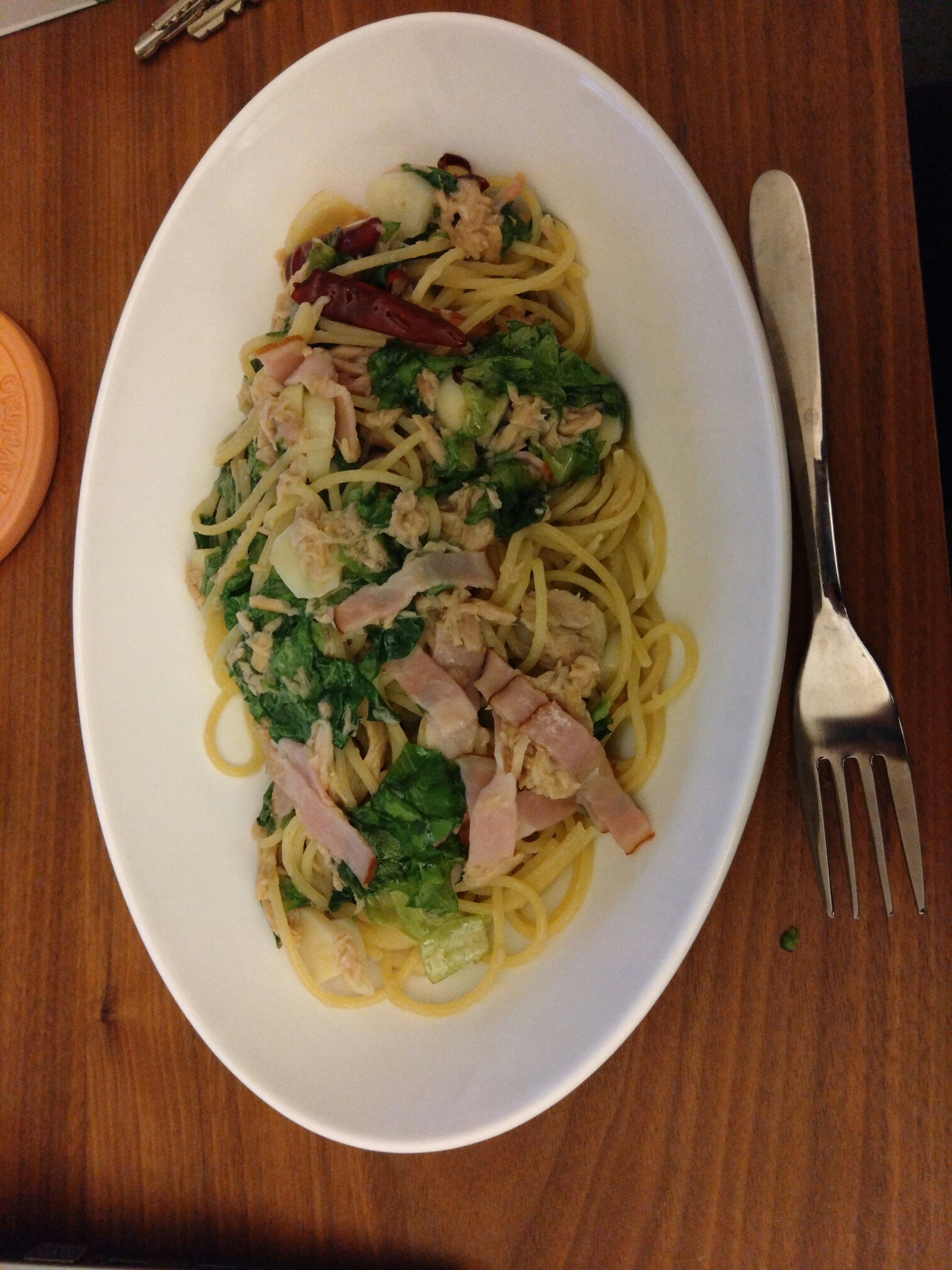 Spaghetti topped with chicken and vegetables on a white plate