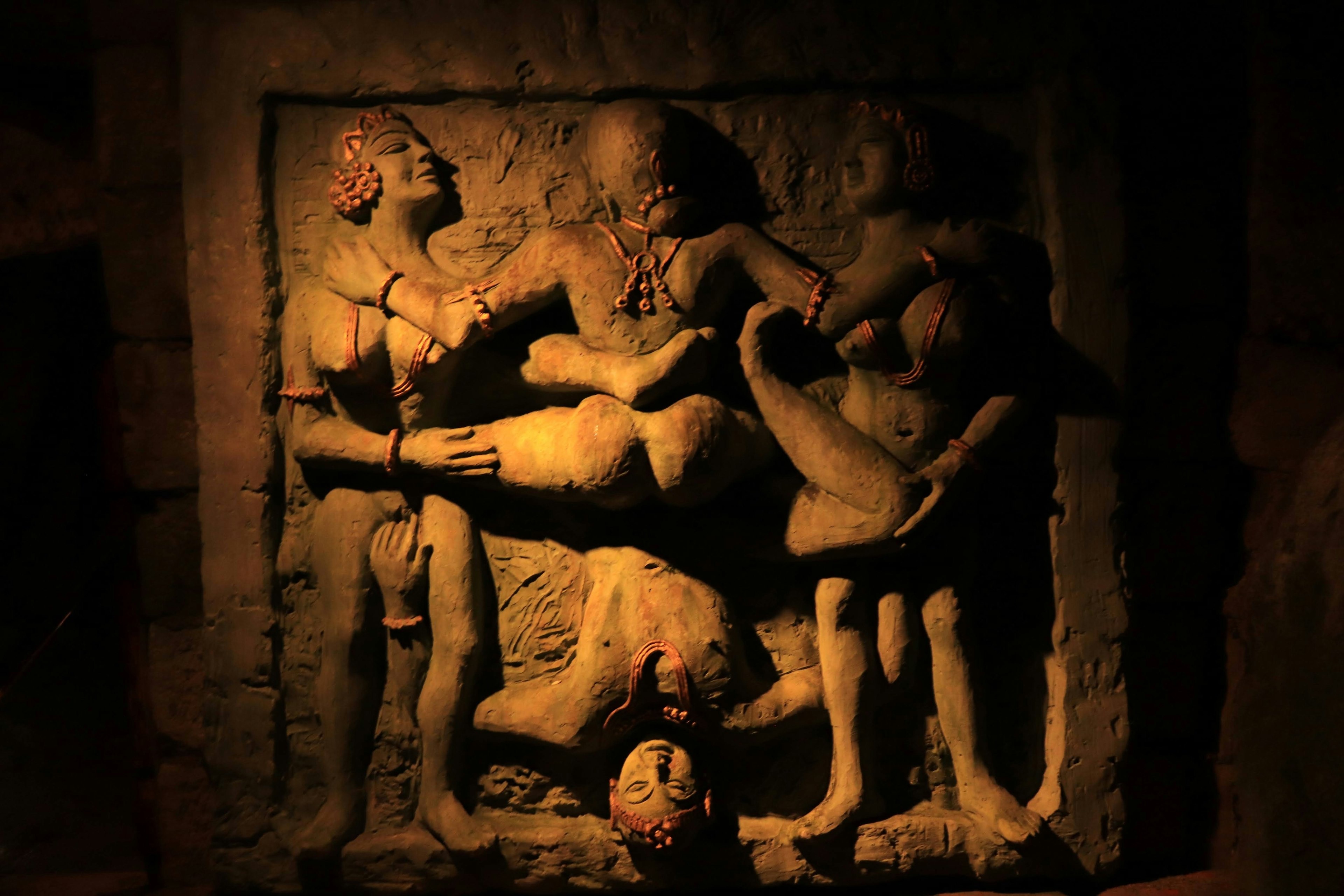 Ancient sculptures in a dark setting, mysterious atmosphere, figures engaged in conversation