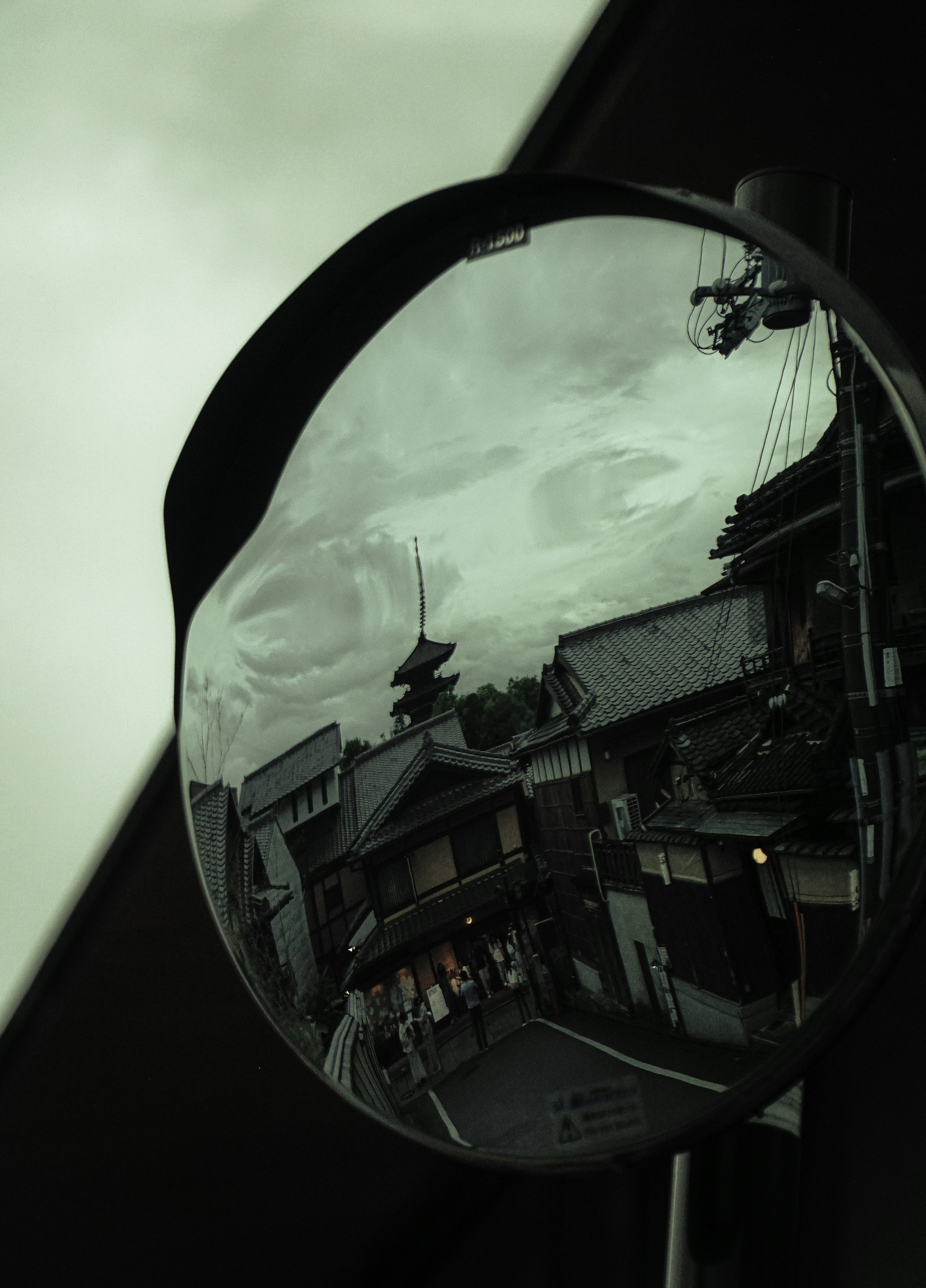 Reflejo en un espejo circular que muestra edificios y cielo nublado