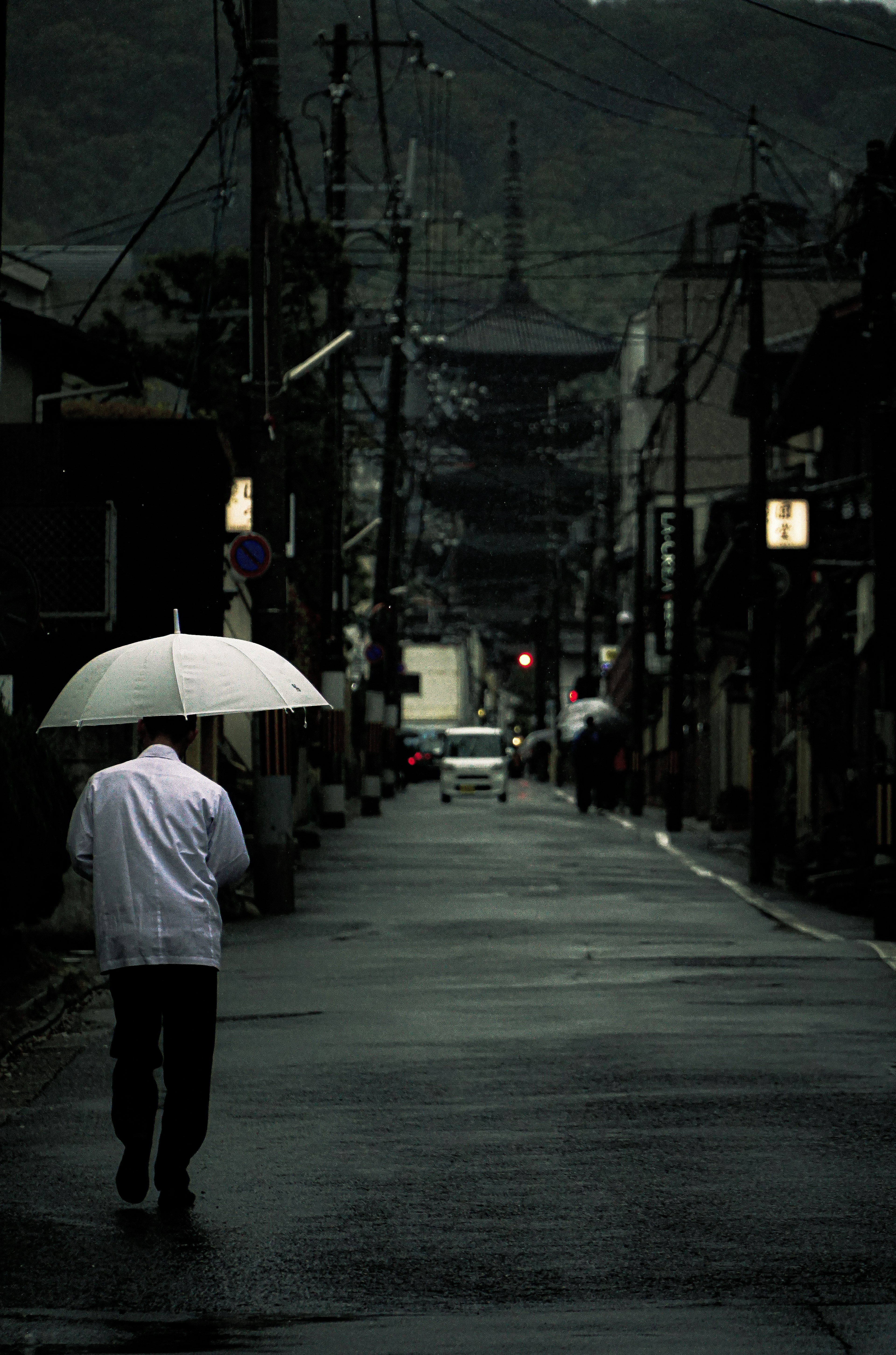 A person walking with a white umbrella on a rainy street