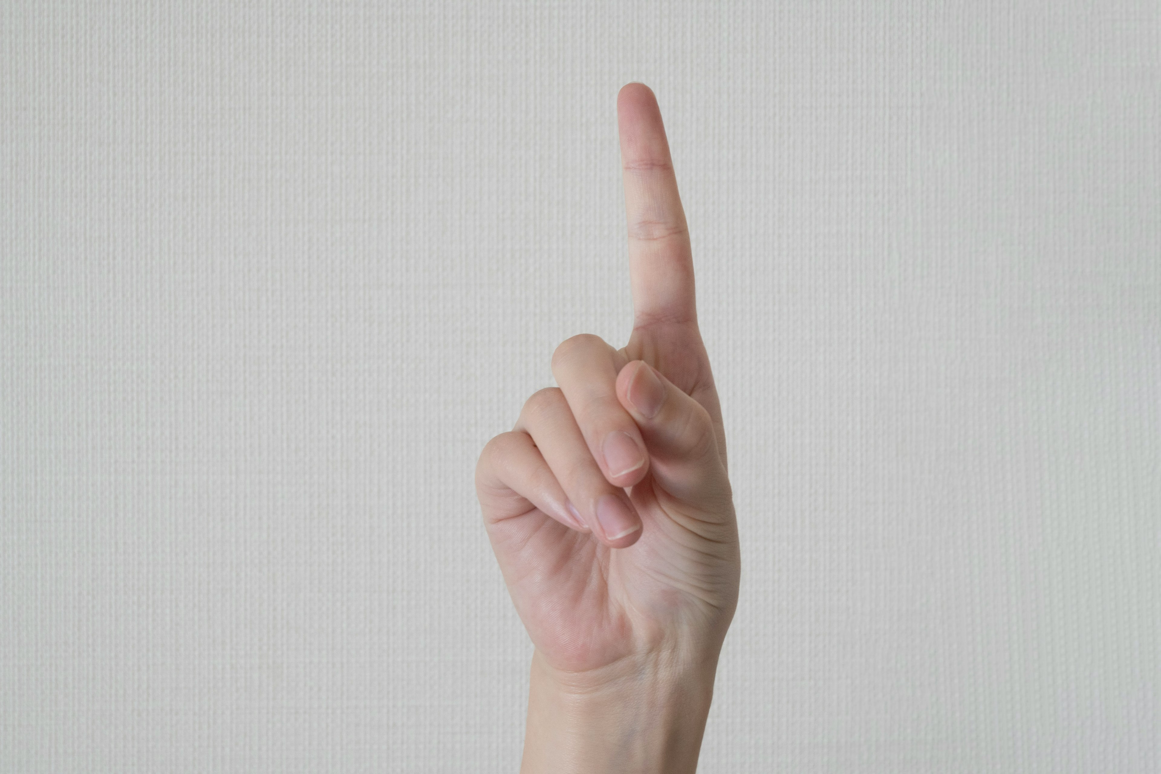 Image of a hand with one finger raised against a plain white background