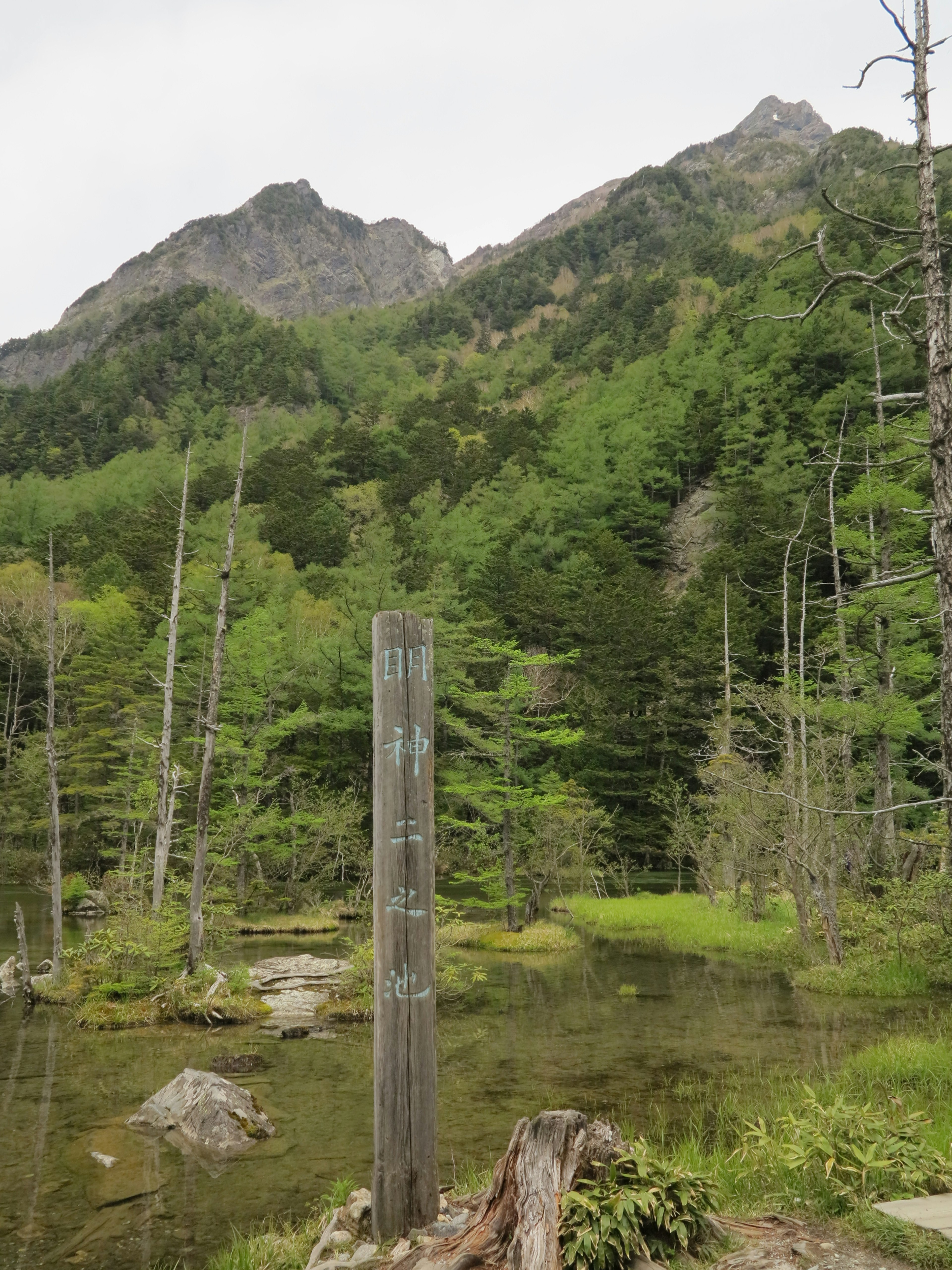 Cartel en un paisaje verde rodeado de montañas y una superficie de agua tranquila