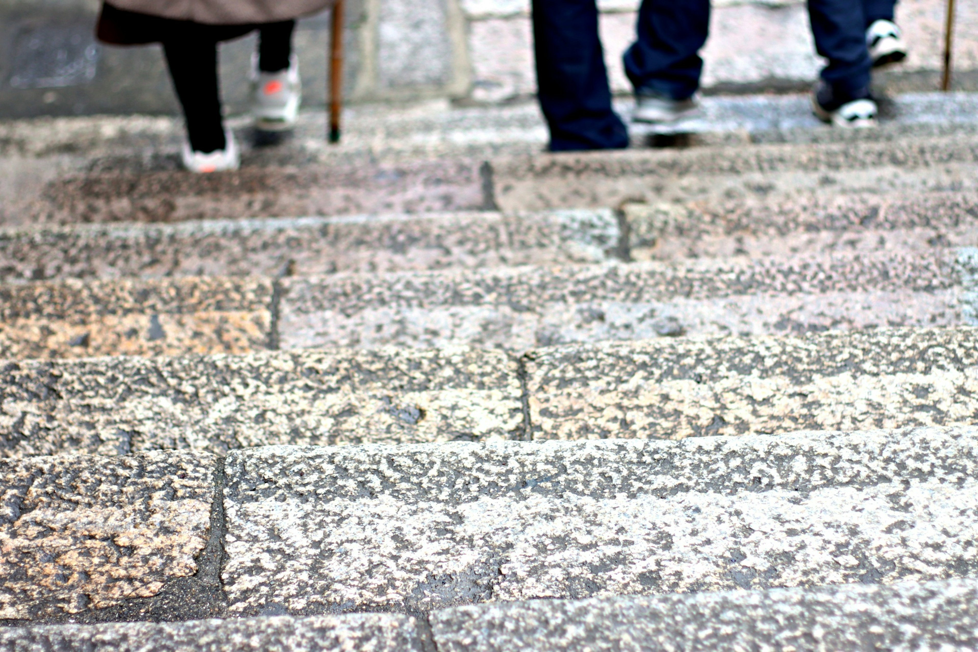 Close-up of feet descending stone stairs with textured surface