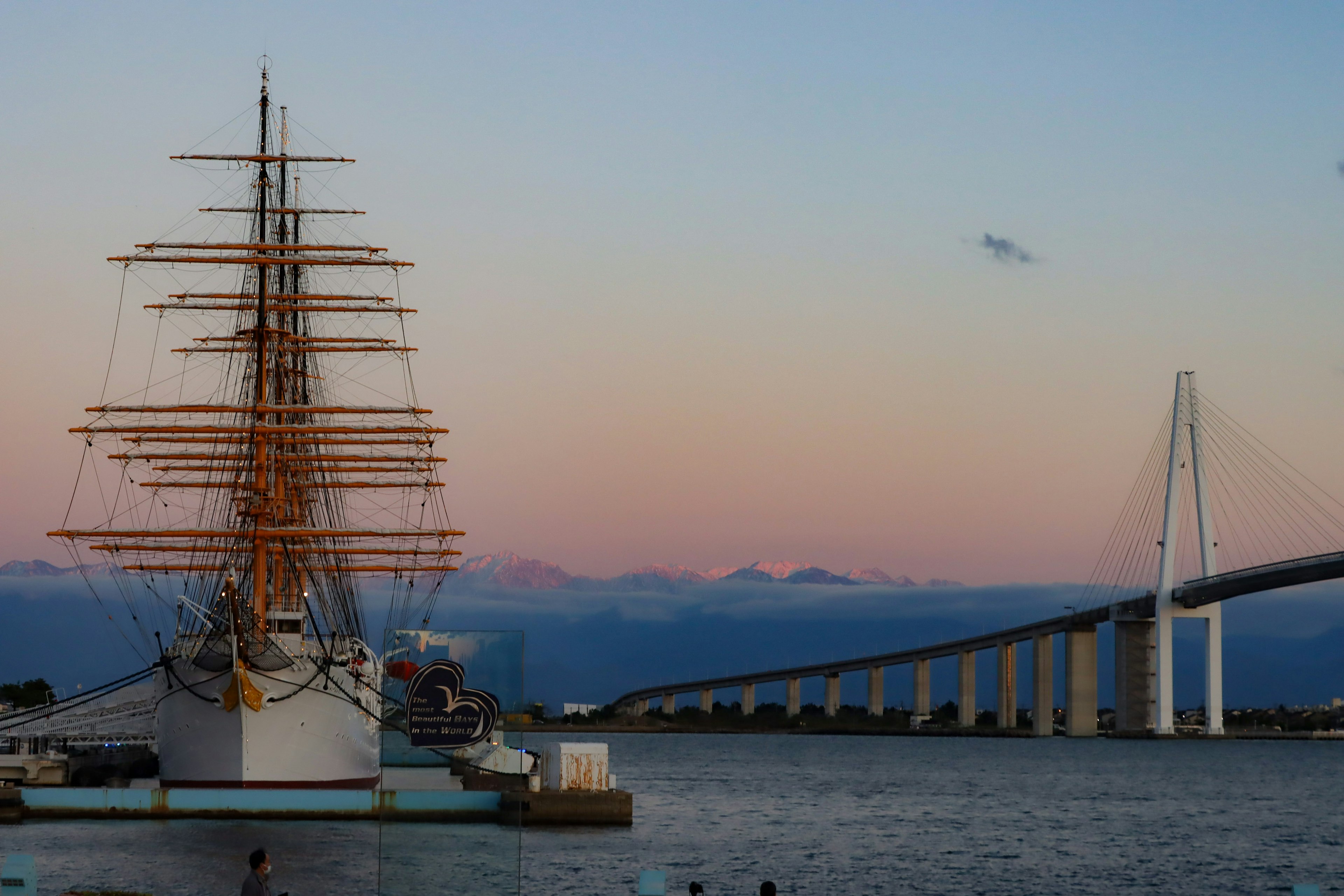 Malersicher Ausblick auf ein Segelschiff und eine Brücke bei wunderschönem Sonnenuntergang