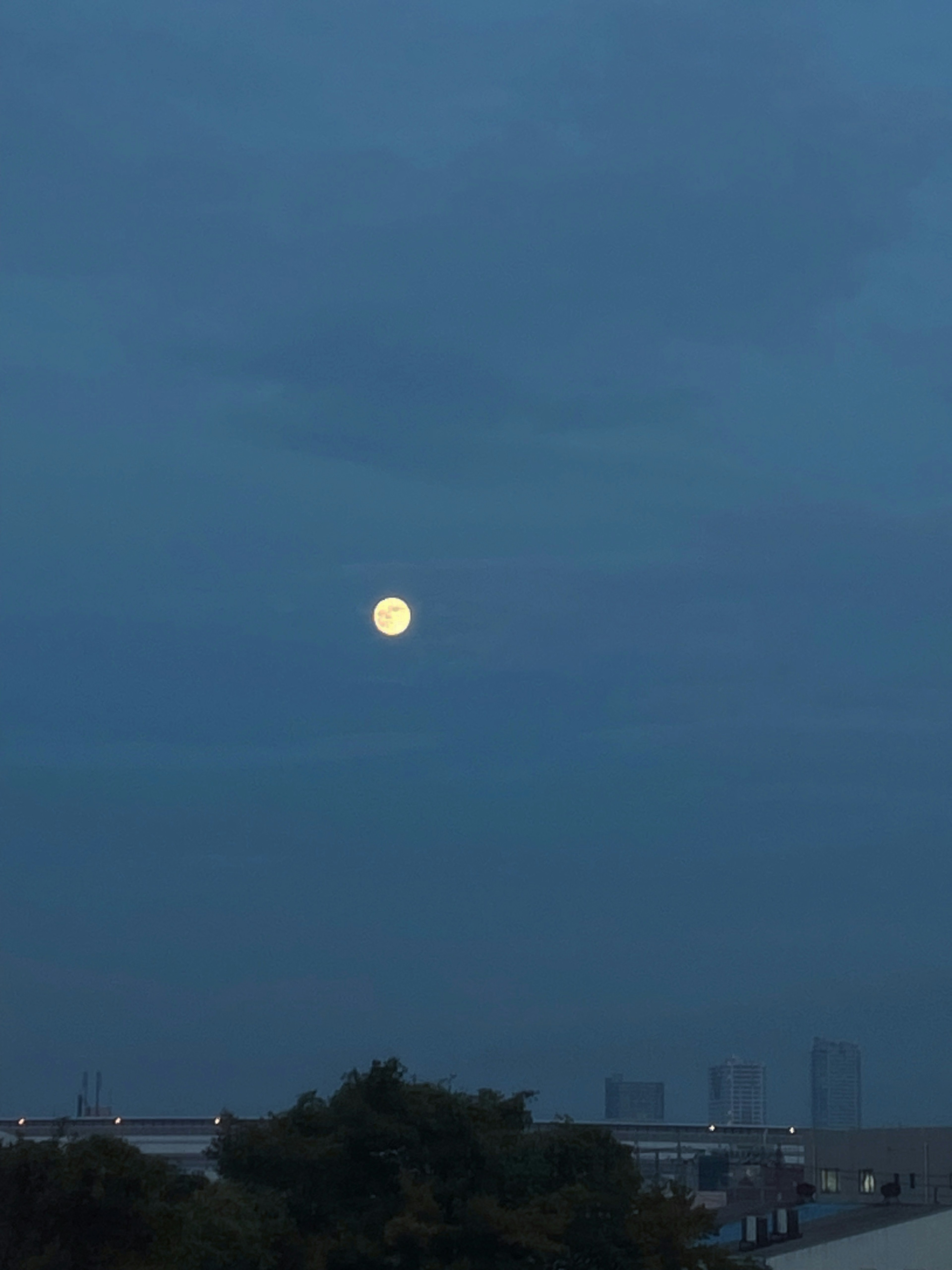 Ein heller Mond in einem blauen Himmel bei Dämmerung