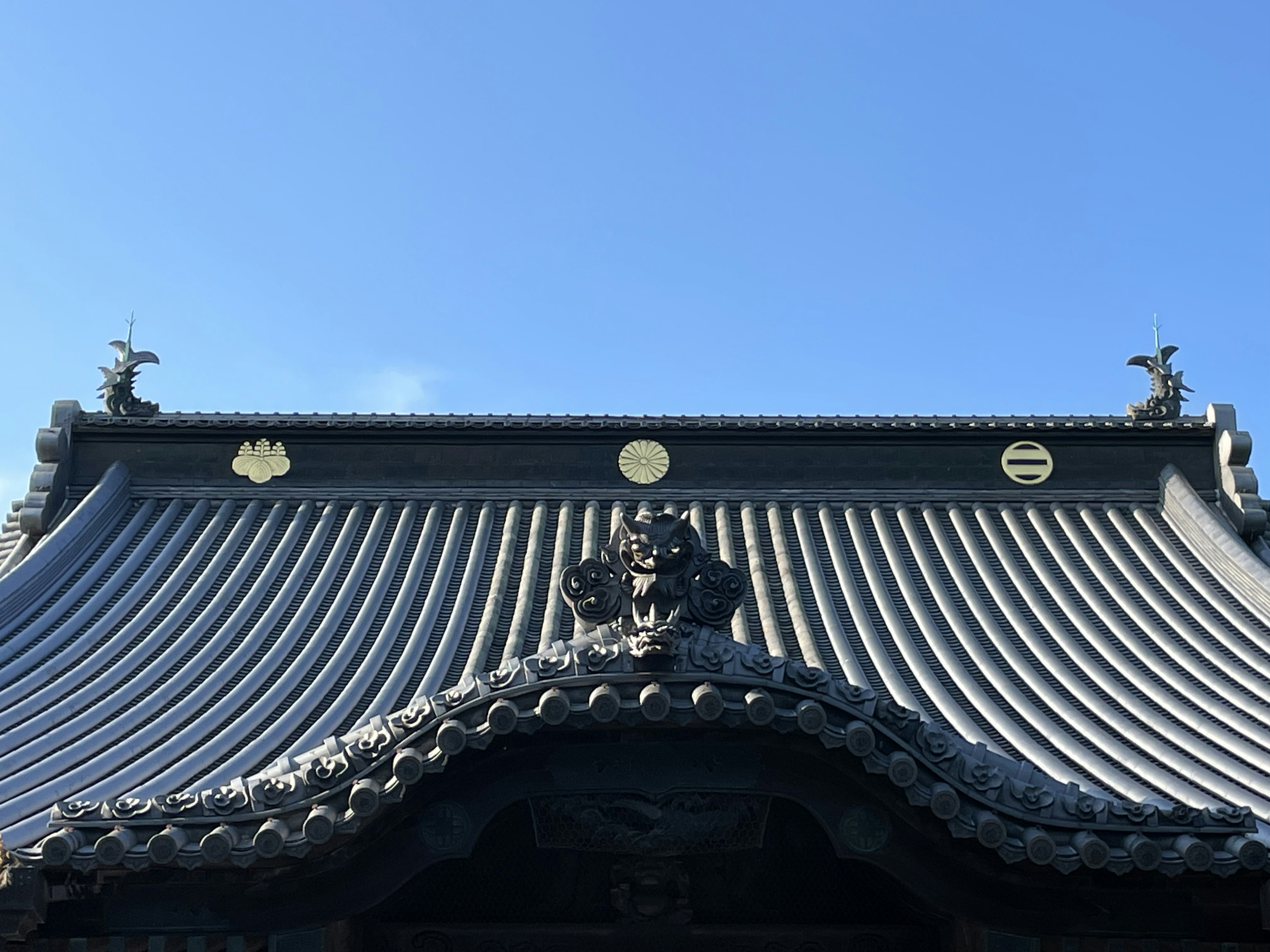 Traditionelles japanisches Gebäude mit gewelltem Dachdesign und goldenen Wappen