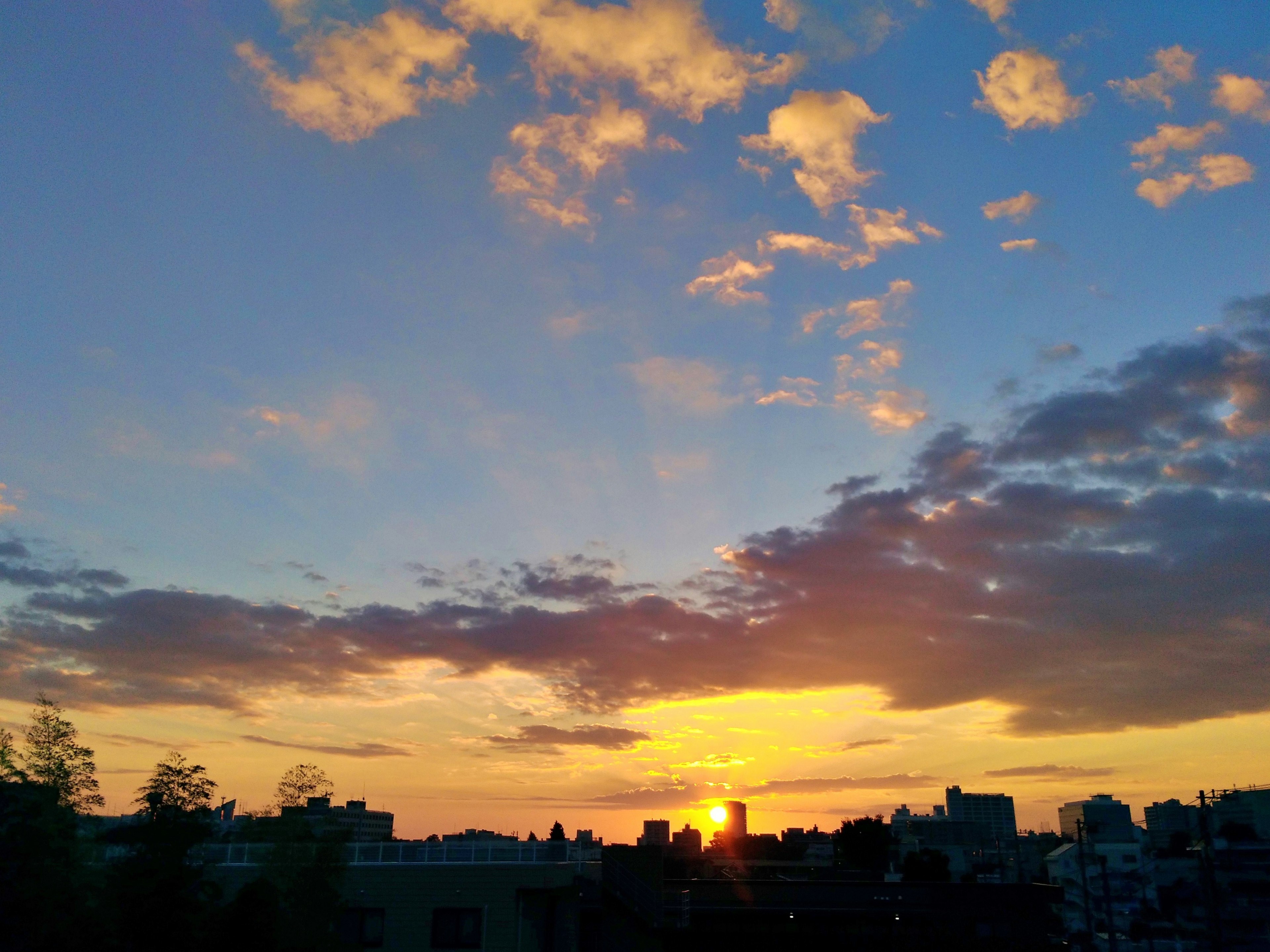 夕日が沈む空に広がる雲とオレンジ色の光