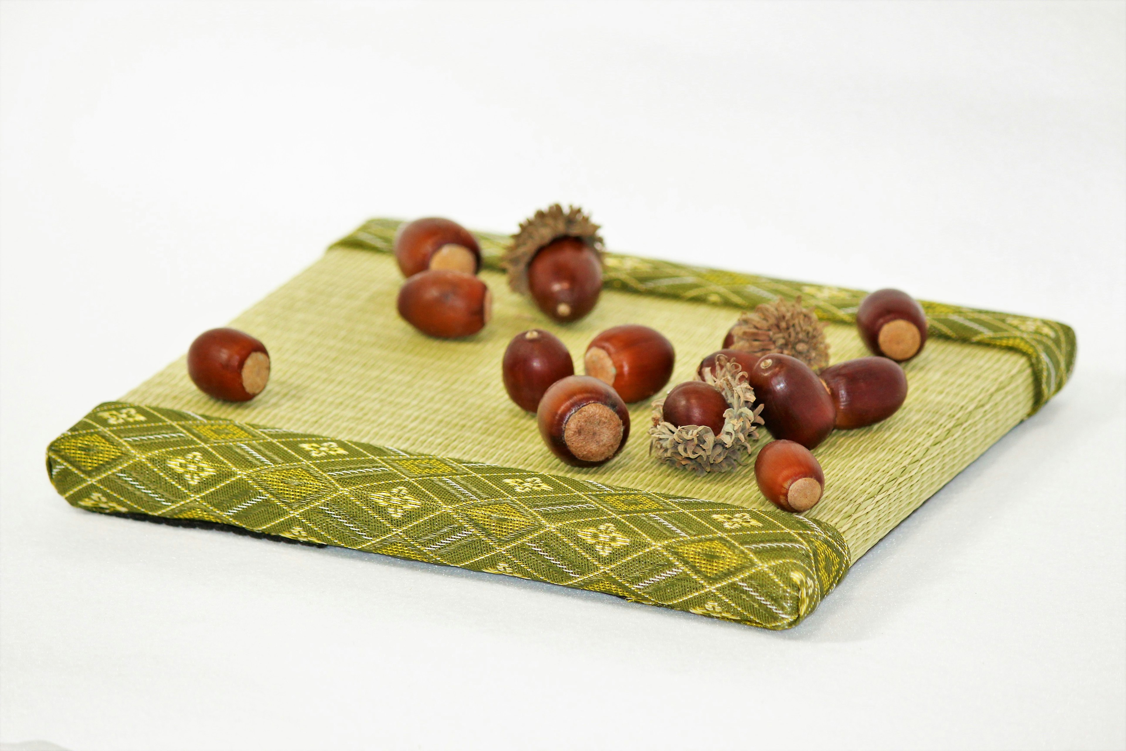 Multiple acorns and their caps scattered on a green cloth