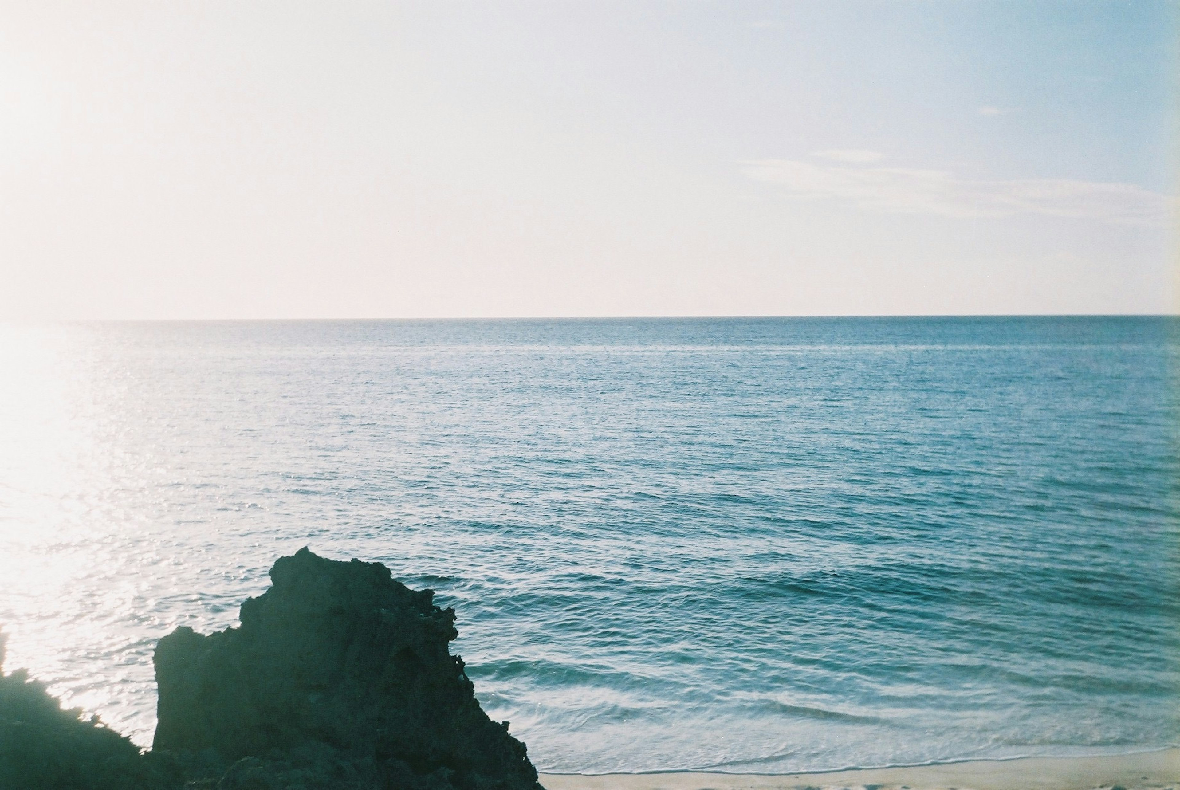 Scenic view of the ocean with a rocky shoreline and clear blue sky