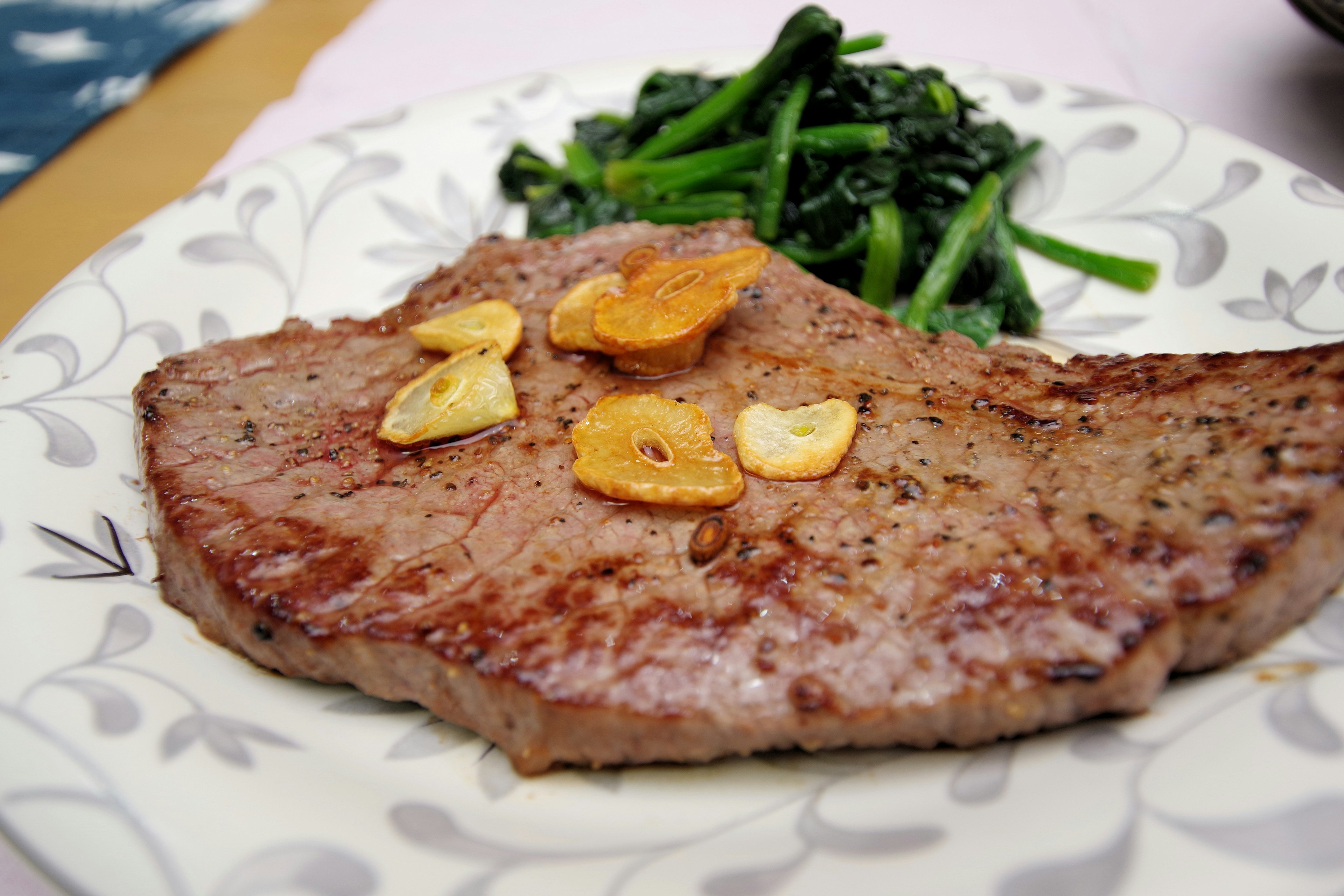 Steak juteux garni de tranches d'ail accompagné de légumes verts