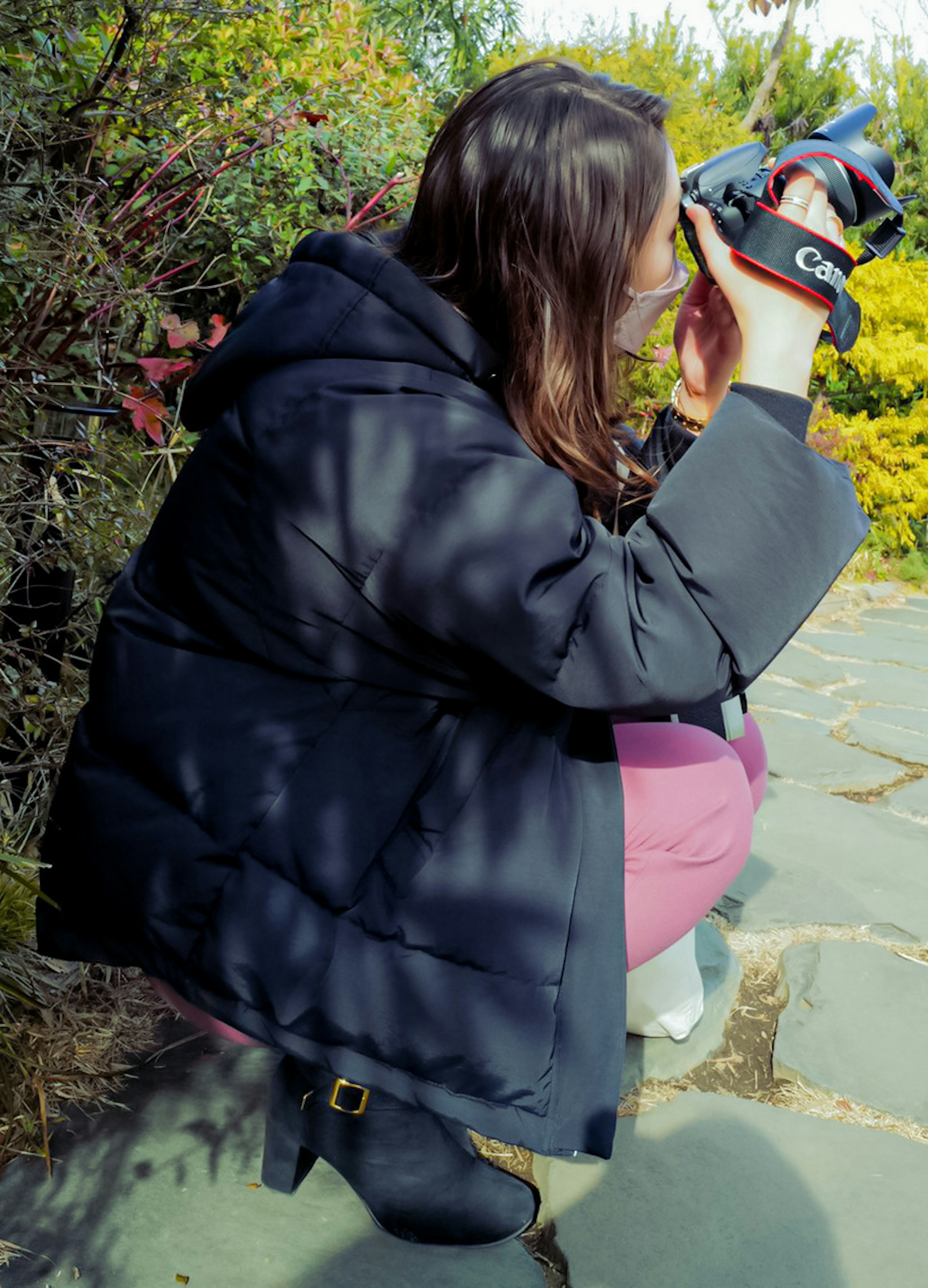 Una donna in un cappotto nero sta scattando una foto con una macchina fotografica