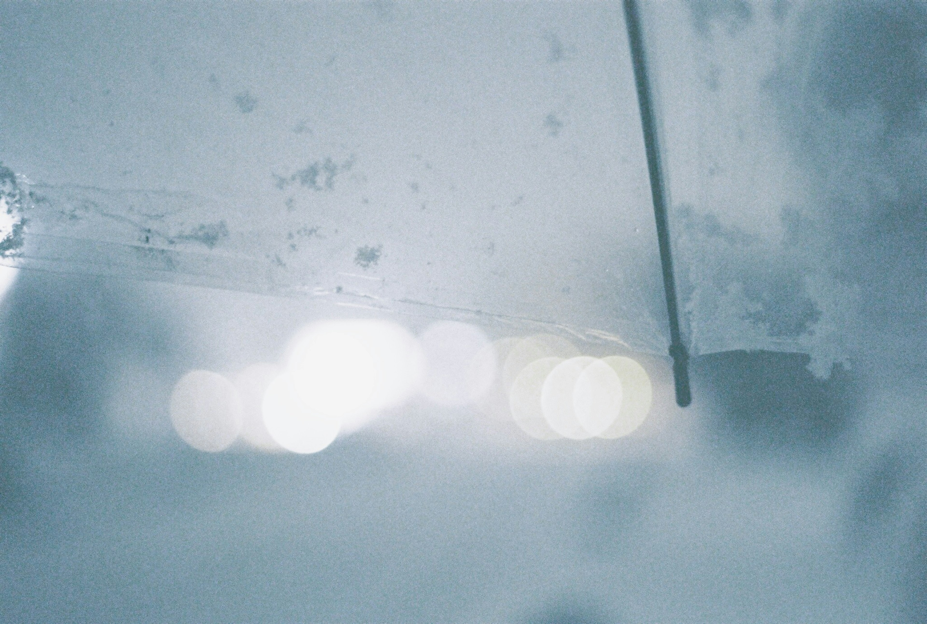 A part of an umbrella visible amidst blue-white light and blurred background