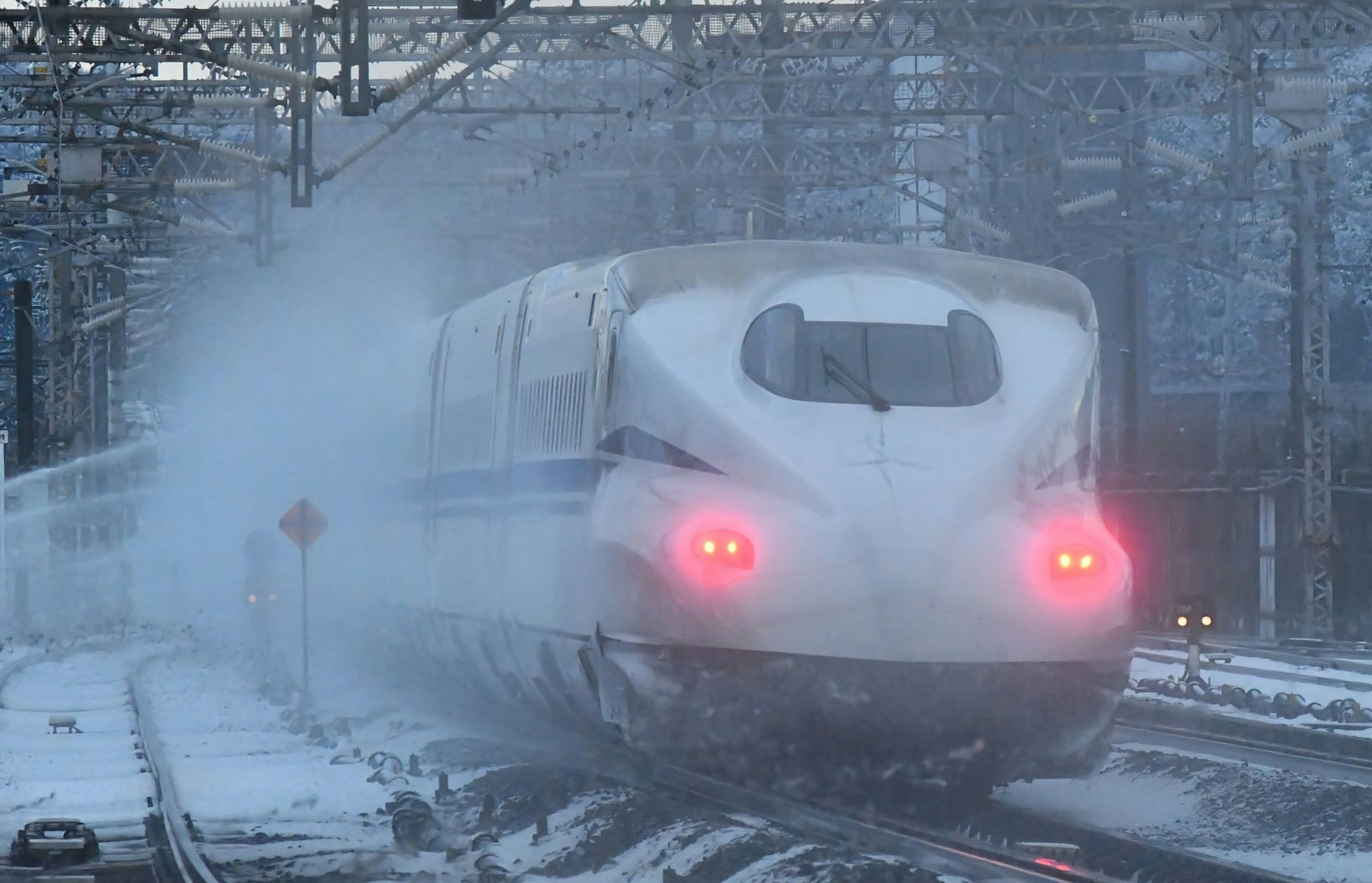 Kereta Shinkansen di salju dengan lampu belakang merah yang terlihat