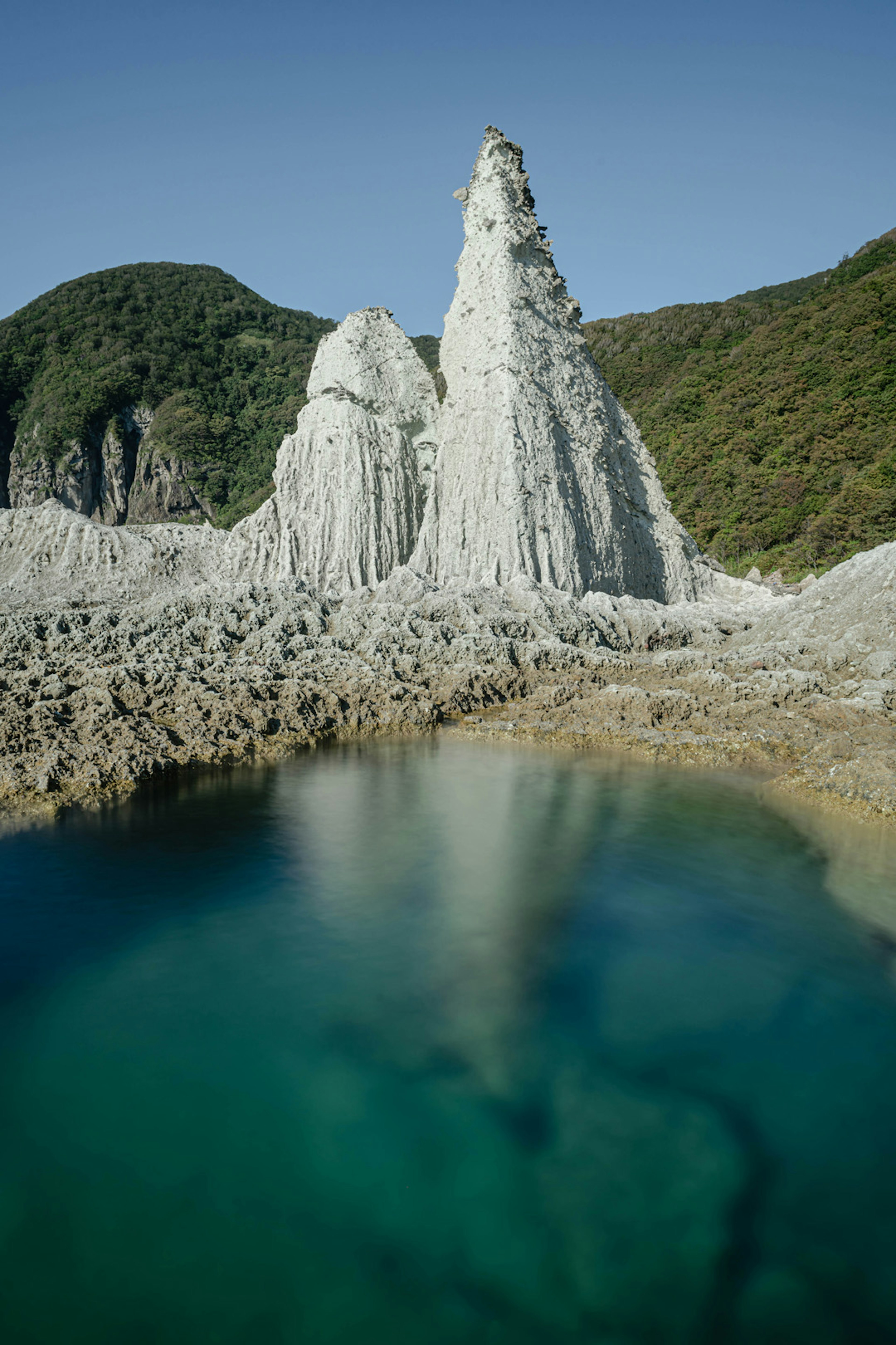 白色岩石形成的風景，周圍是綠色山丘和清澈藍色水域