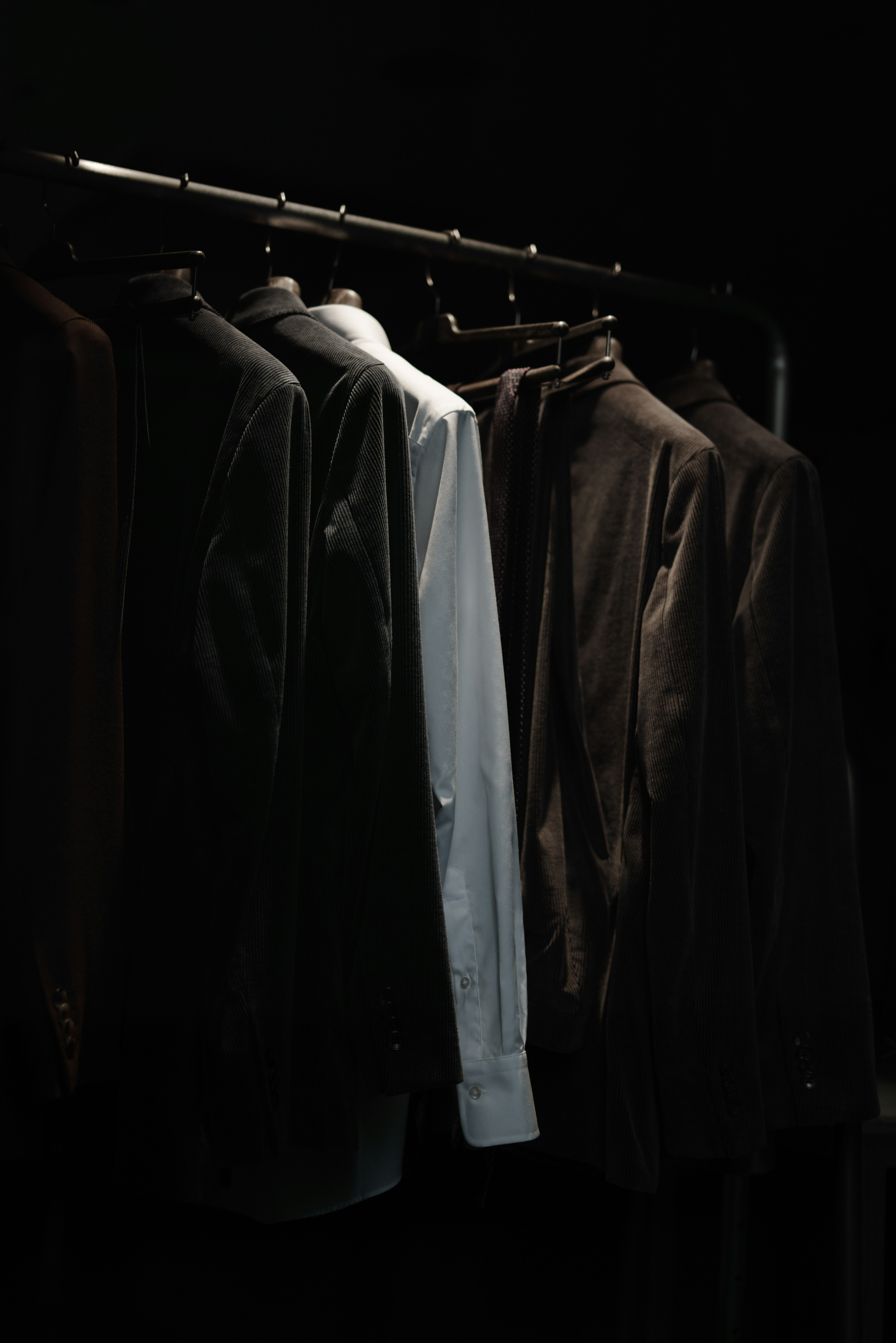 A clothing rack displaying a white shirt alongside dark-colored jackets