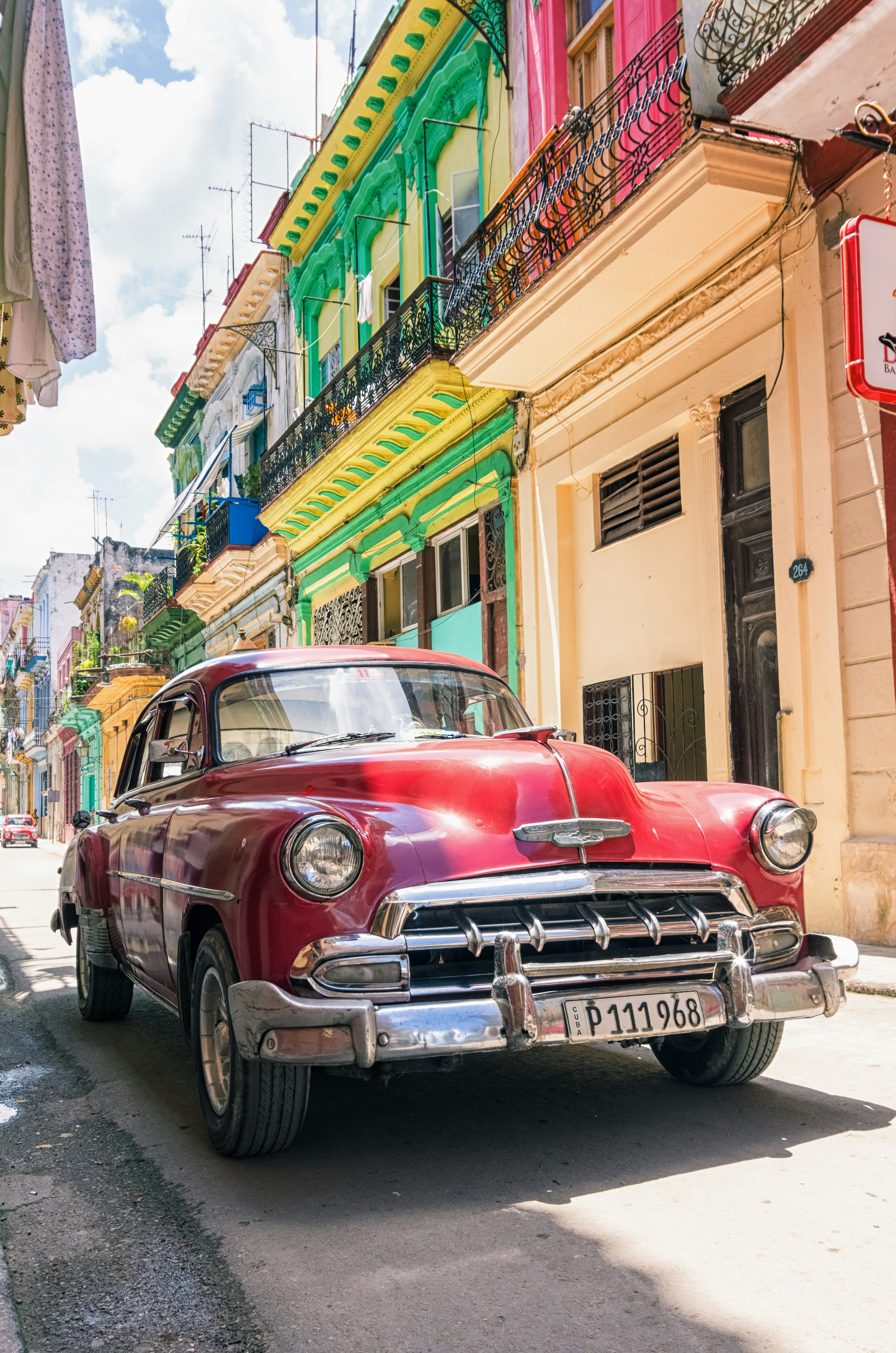 Colorful buildings and a vintage red car in the streets of Havana