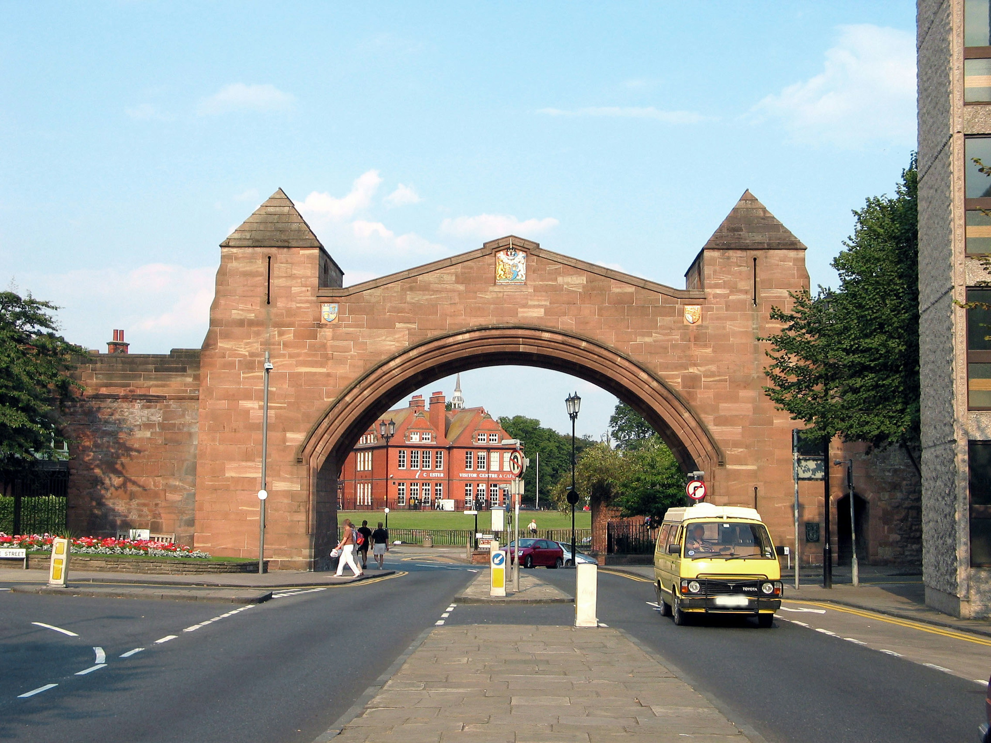 Archway made of red stone with surrounding street scene