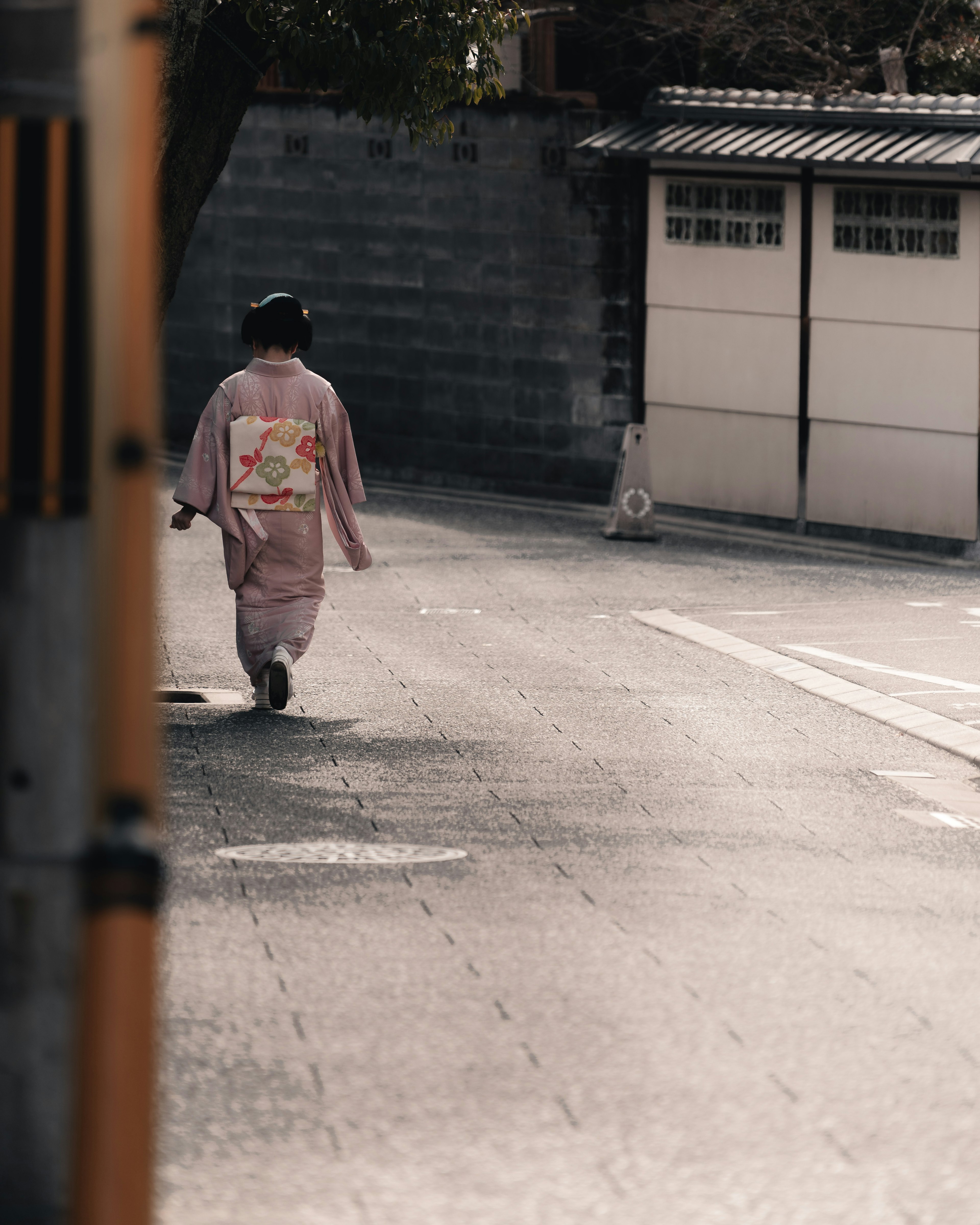 Eine Frau in einem traditionellen japanischen Kimono, die eine ruhige Straße entlanggeht