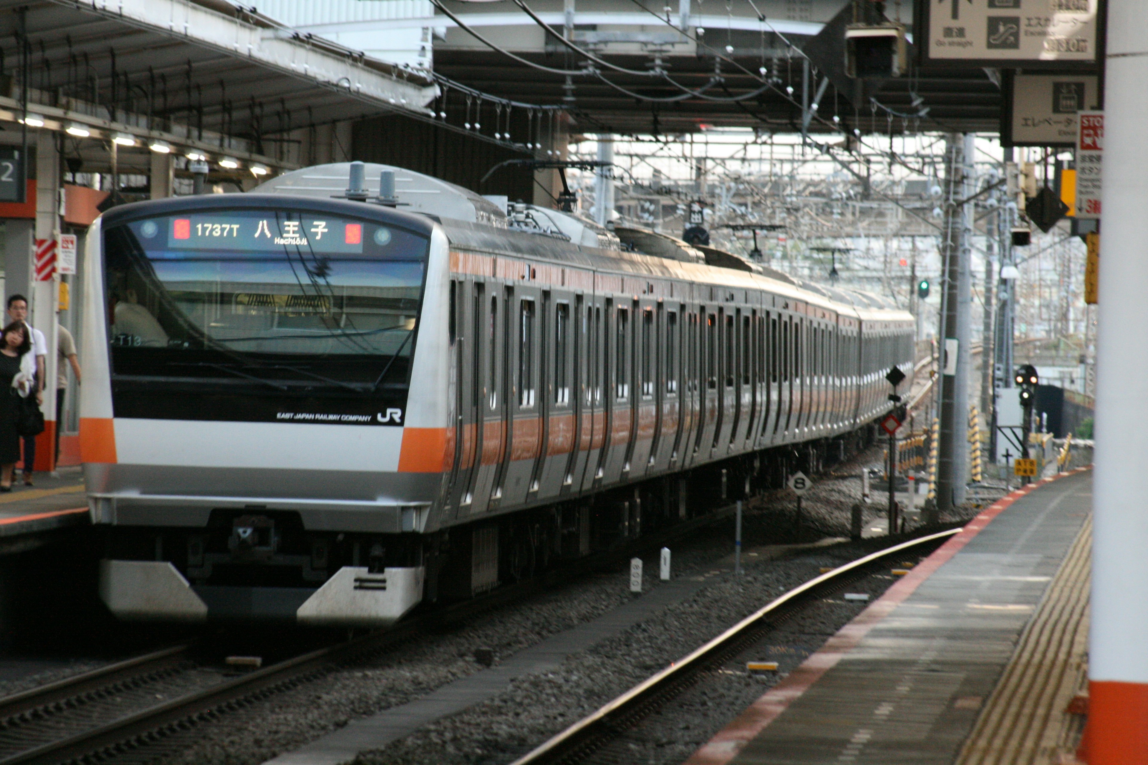 Bild eines an einem japanischen Bahnhof haltenden Zuges mit modernem Design und orangefarbenen Streifen