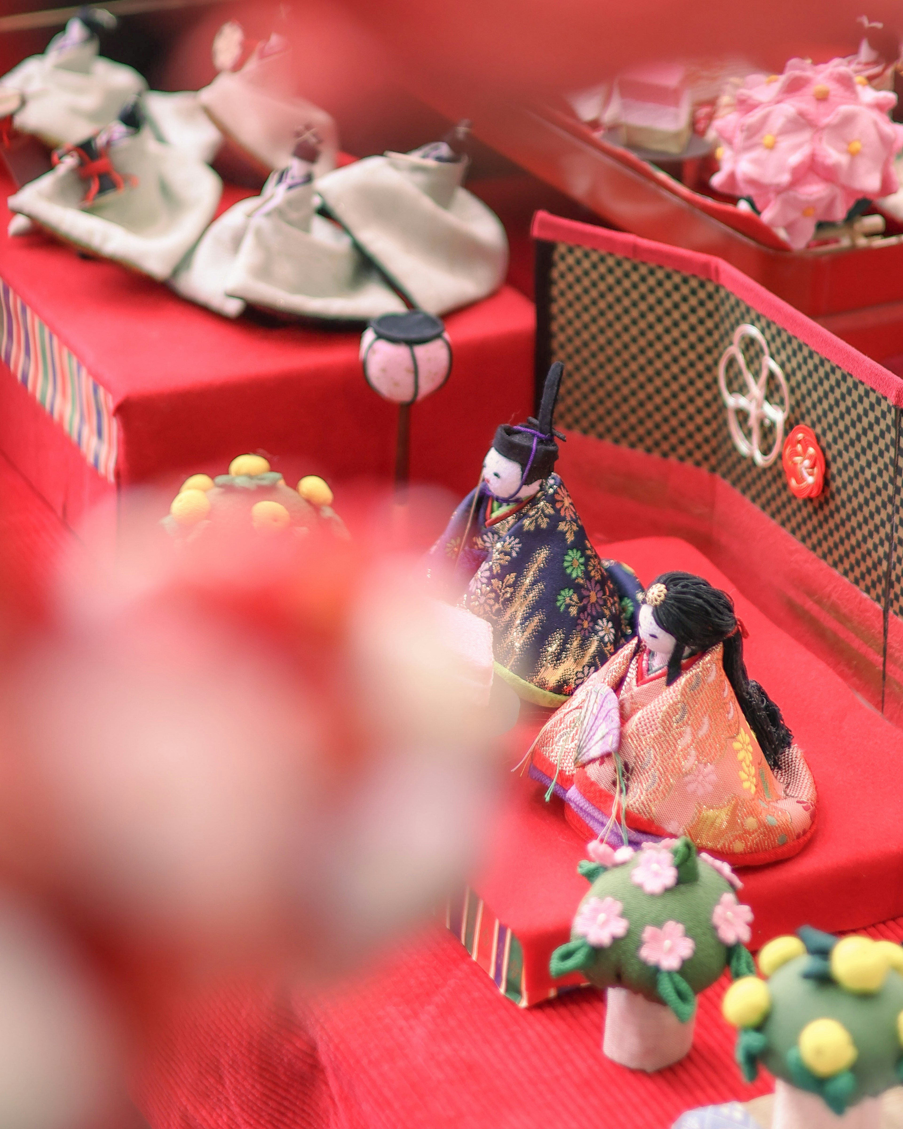 Hinamatsuri-Puppen mit bunten Blumendekorationen auf einer roten Plattform