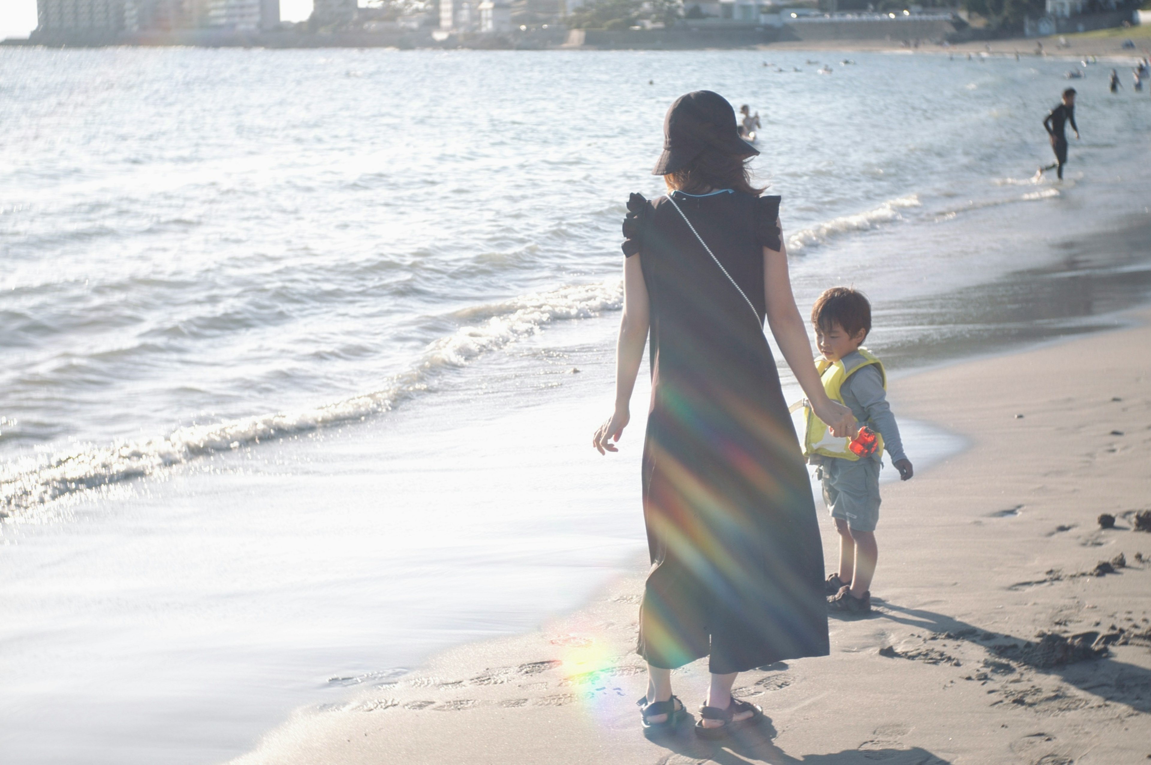 Silhouette einer Mutter und eines Kindes, die am Strand mit Sonnenlicht gehen