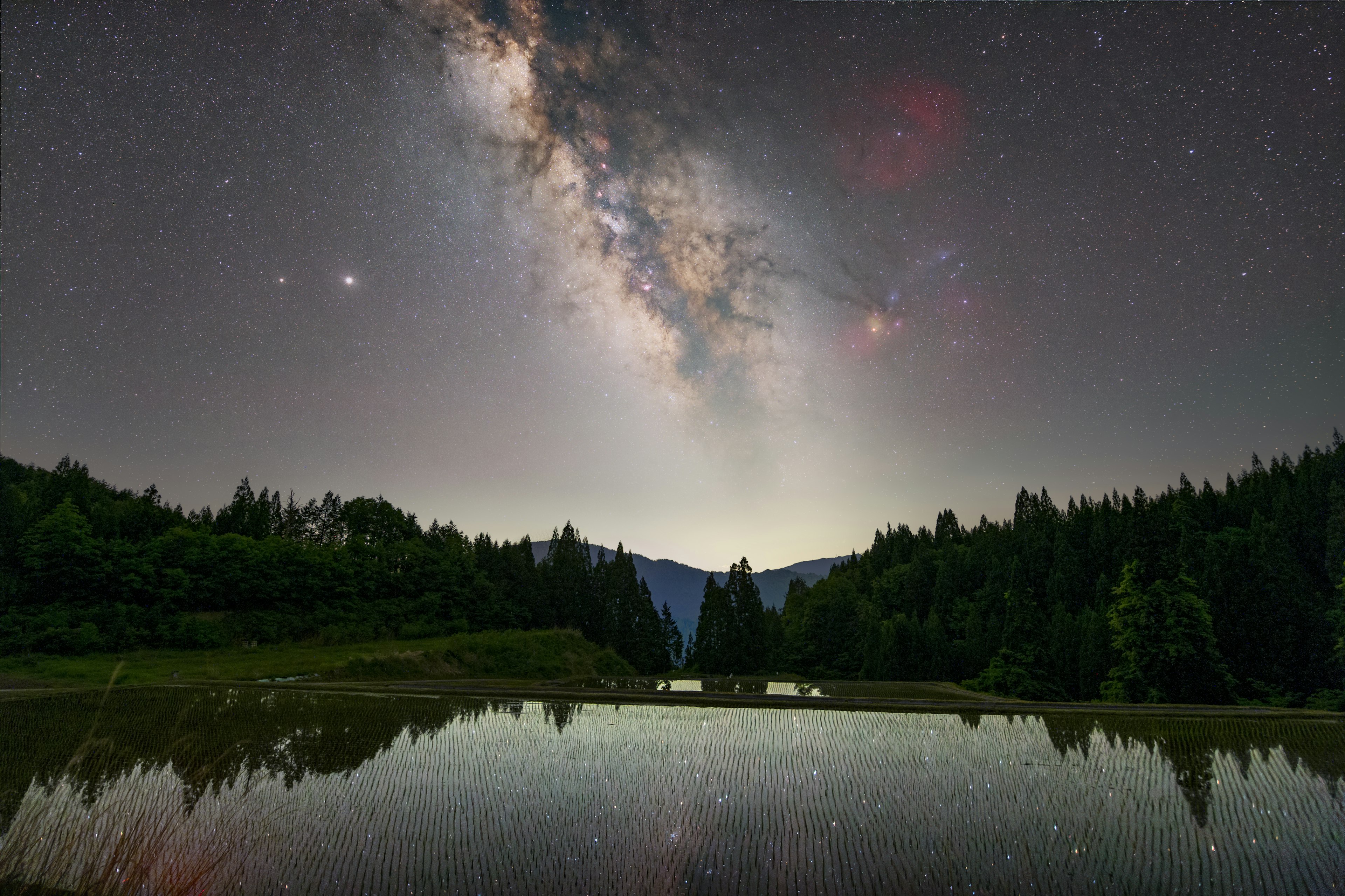 Un lago sereno reflejando la Vía Láctea y el cielo estrellado