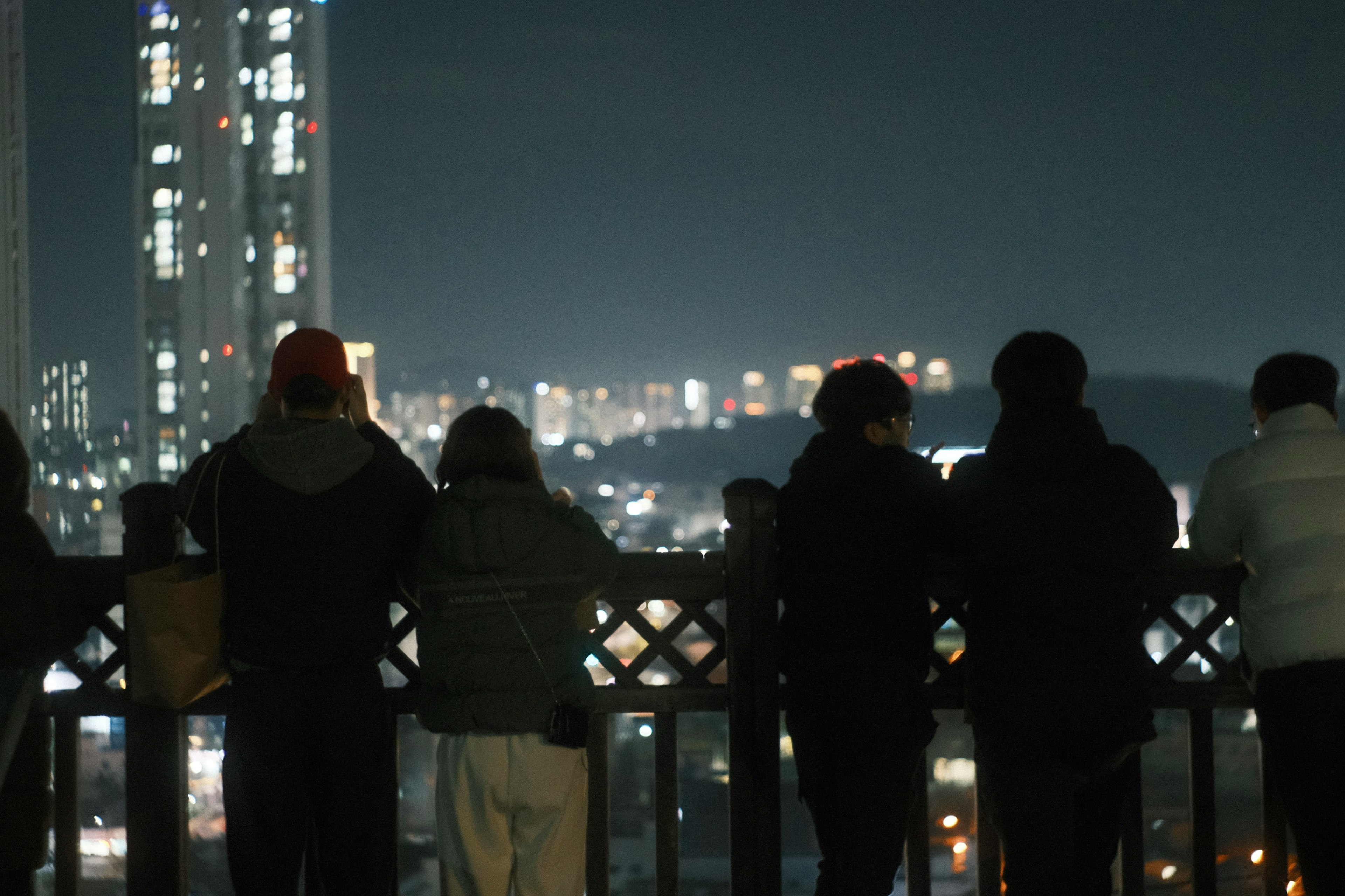 Silhouettes de personnes regardant une ligne d'horizon urbaine la nuit