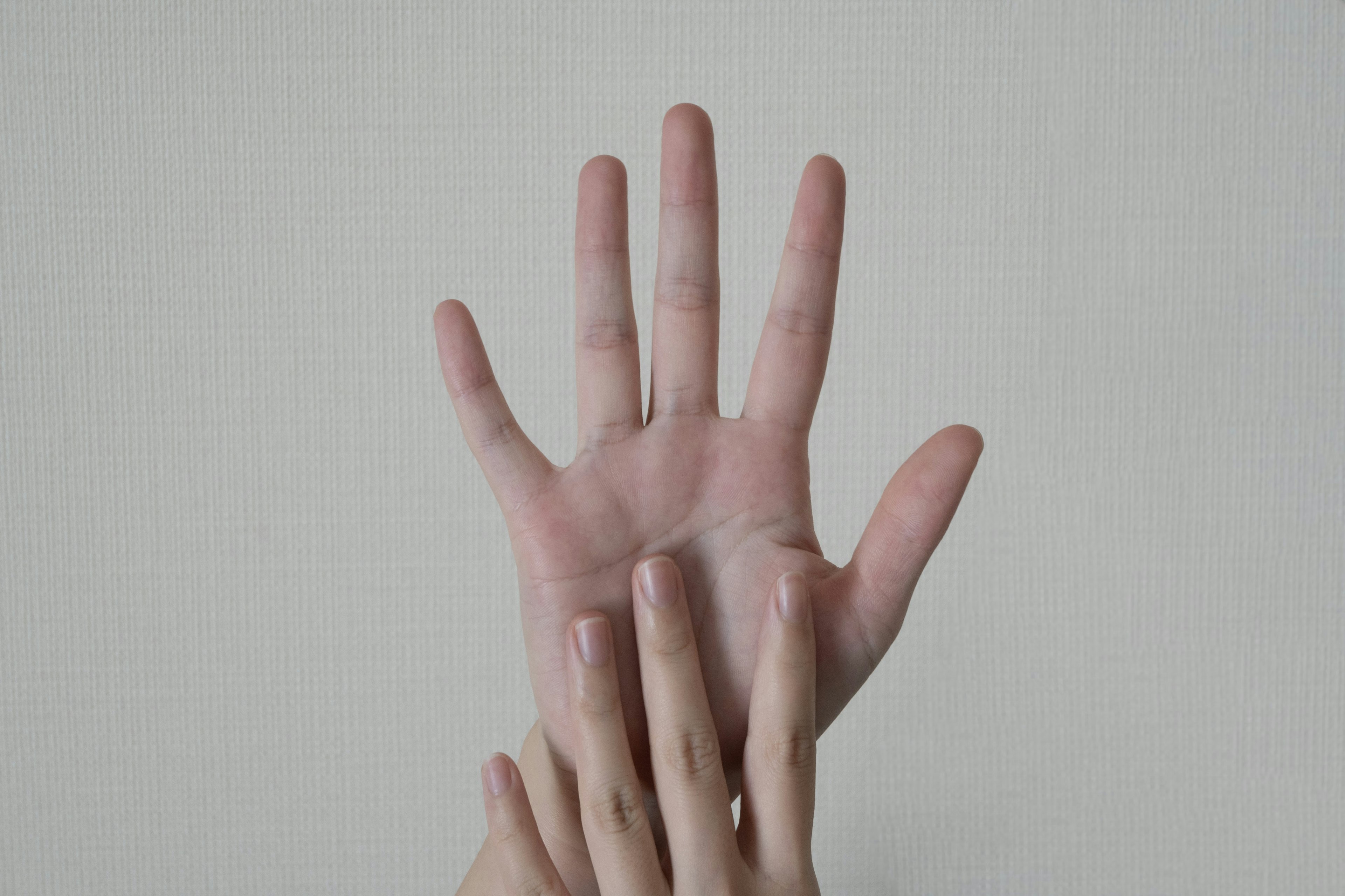 A large hand with palm facing up overlapping a smaller hand