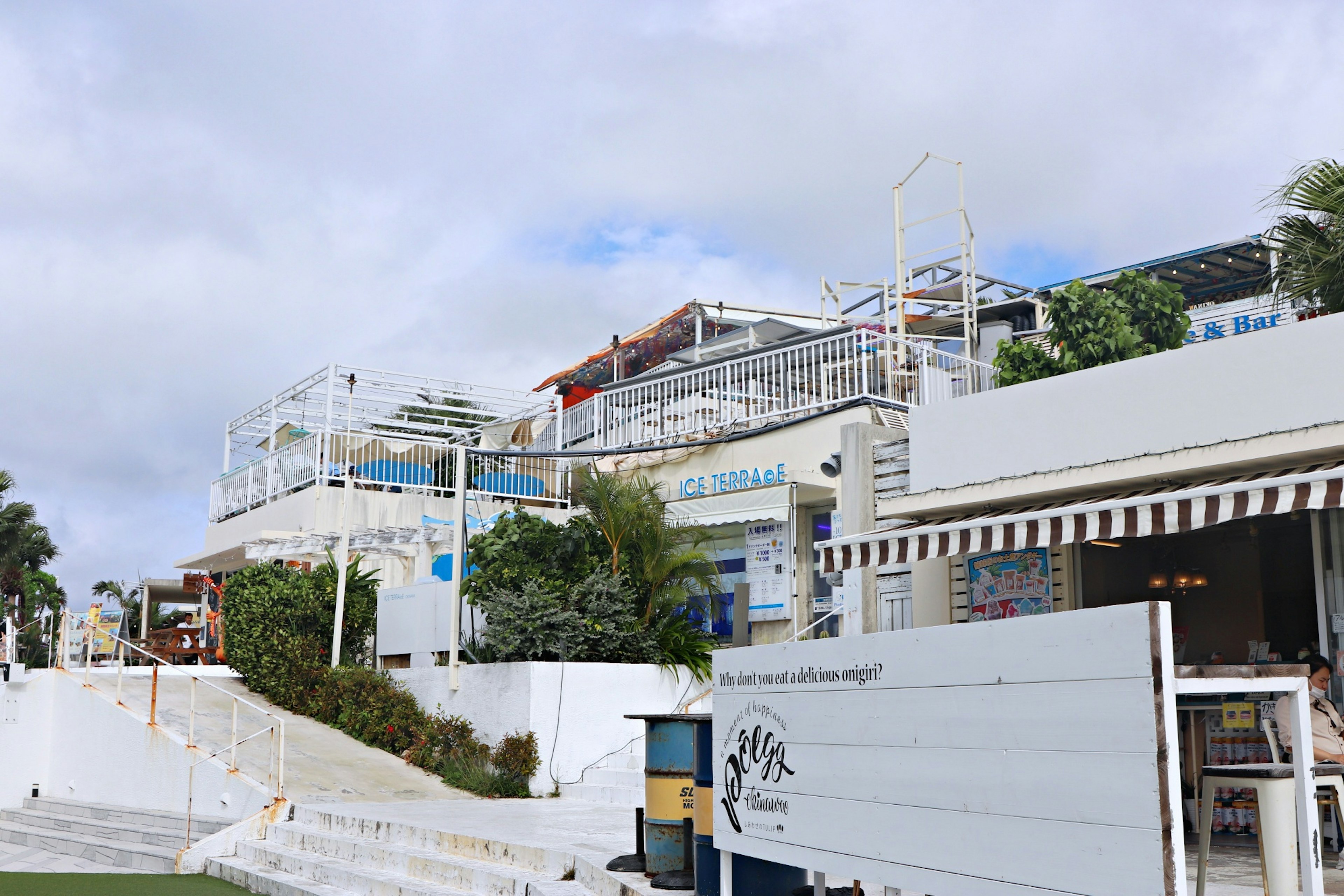 海濱景觀，白色建築和綠植，有咖啡館和餐廳