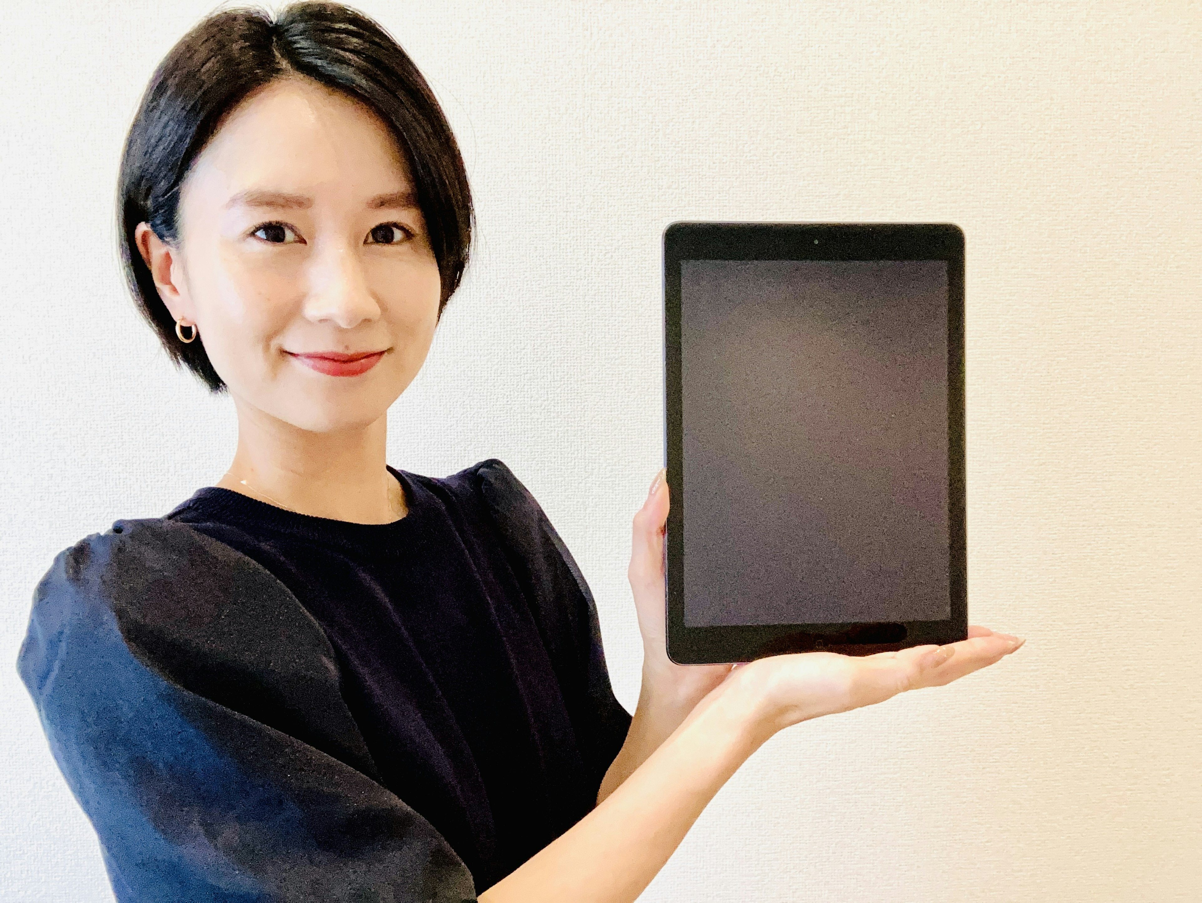 Une femme souriante tenant une tablette sur fond simple